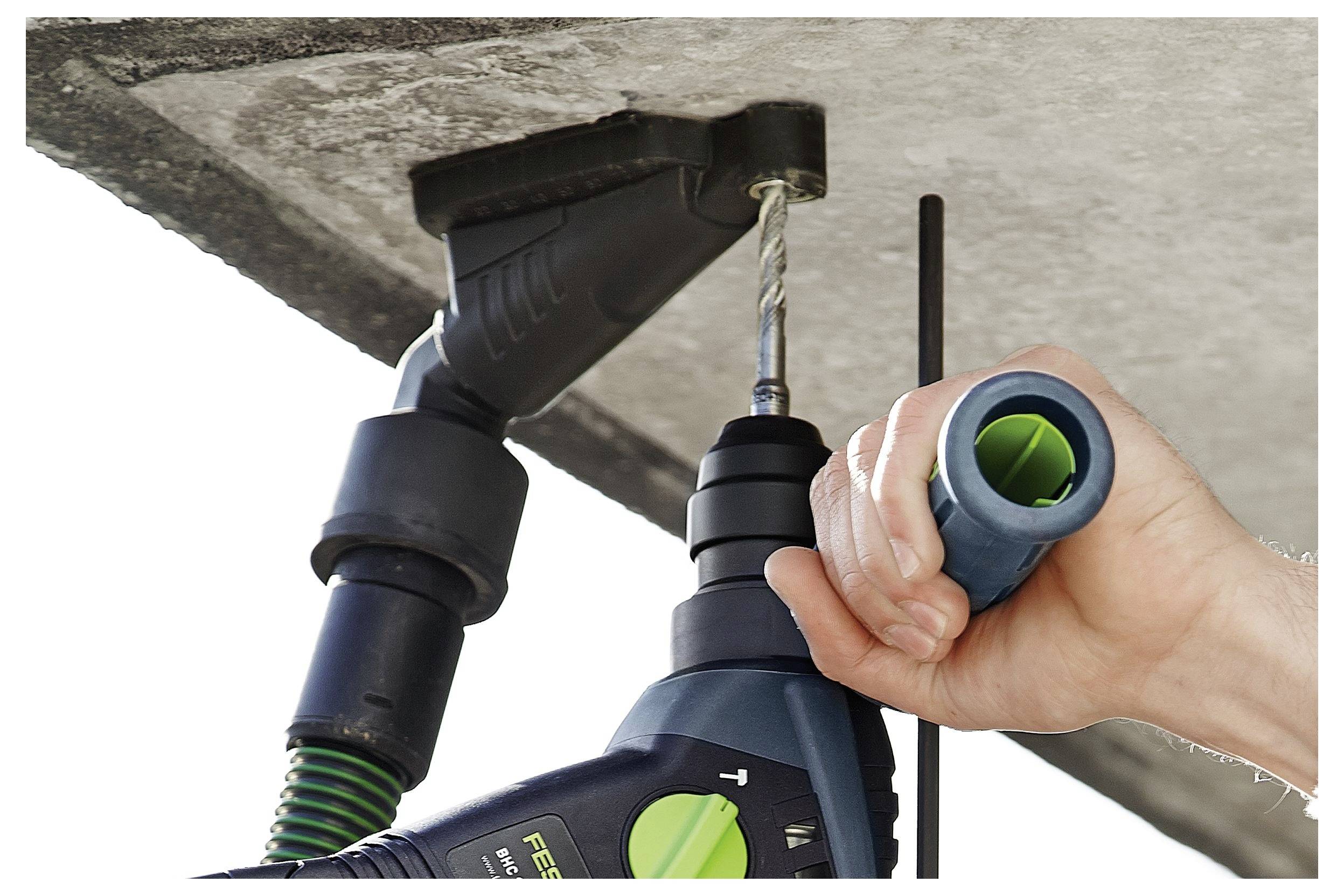 Eine Person verwendet einen Elektroschrauber, um ein Loch in eine Betondecke zu bohren, während sie eine Werkzeuganlage zur Staubabsaugung hält.
