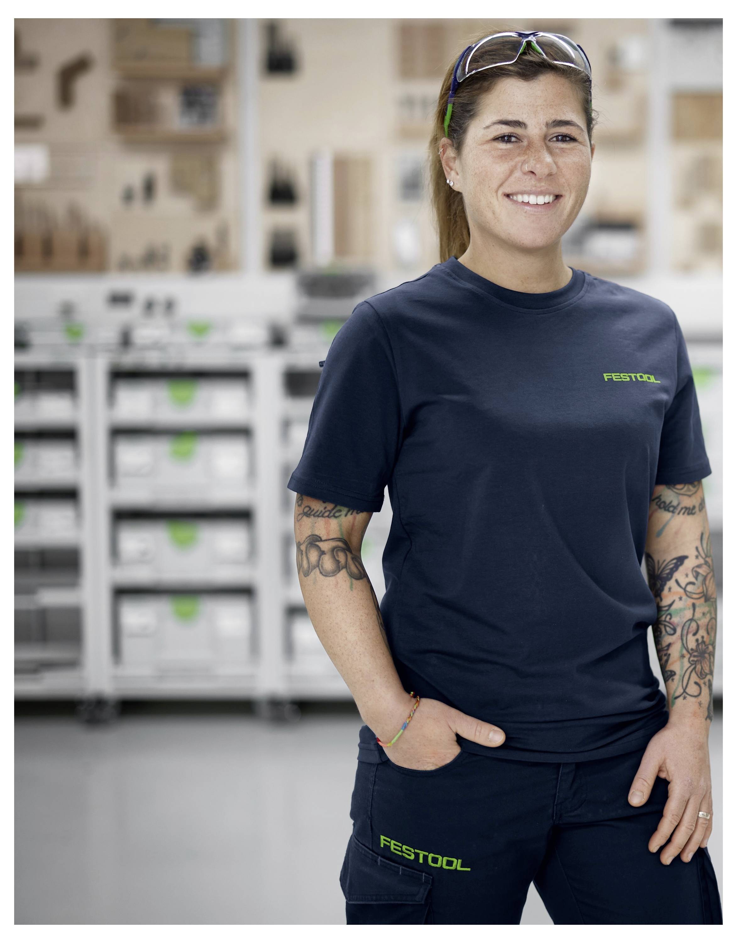 Eine Person bedient eine Holzbearbeitungsfräsmaschine und führt sie entlang einer Schiene in einer Werkstatt, wobei sie sich auf Präzision und Details in der Handwerkskunst konzentriert.