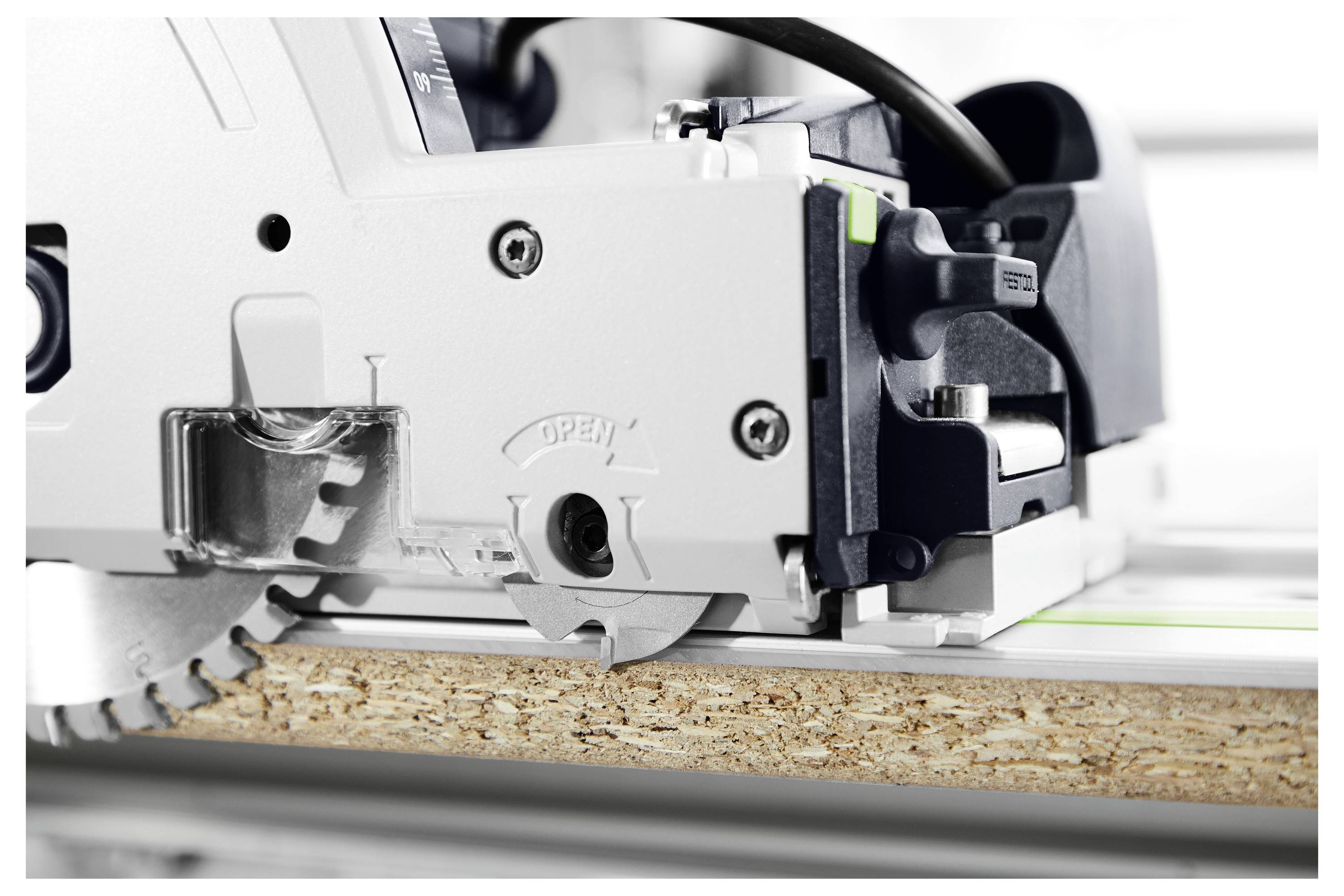 Eine Kreissäge, die durch ein Stück Holz schneidet, zeigt die Klinge und Maschinendetails; die Holzkante ist unter der Säge sichtbar.