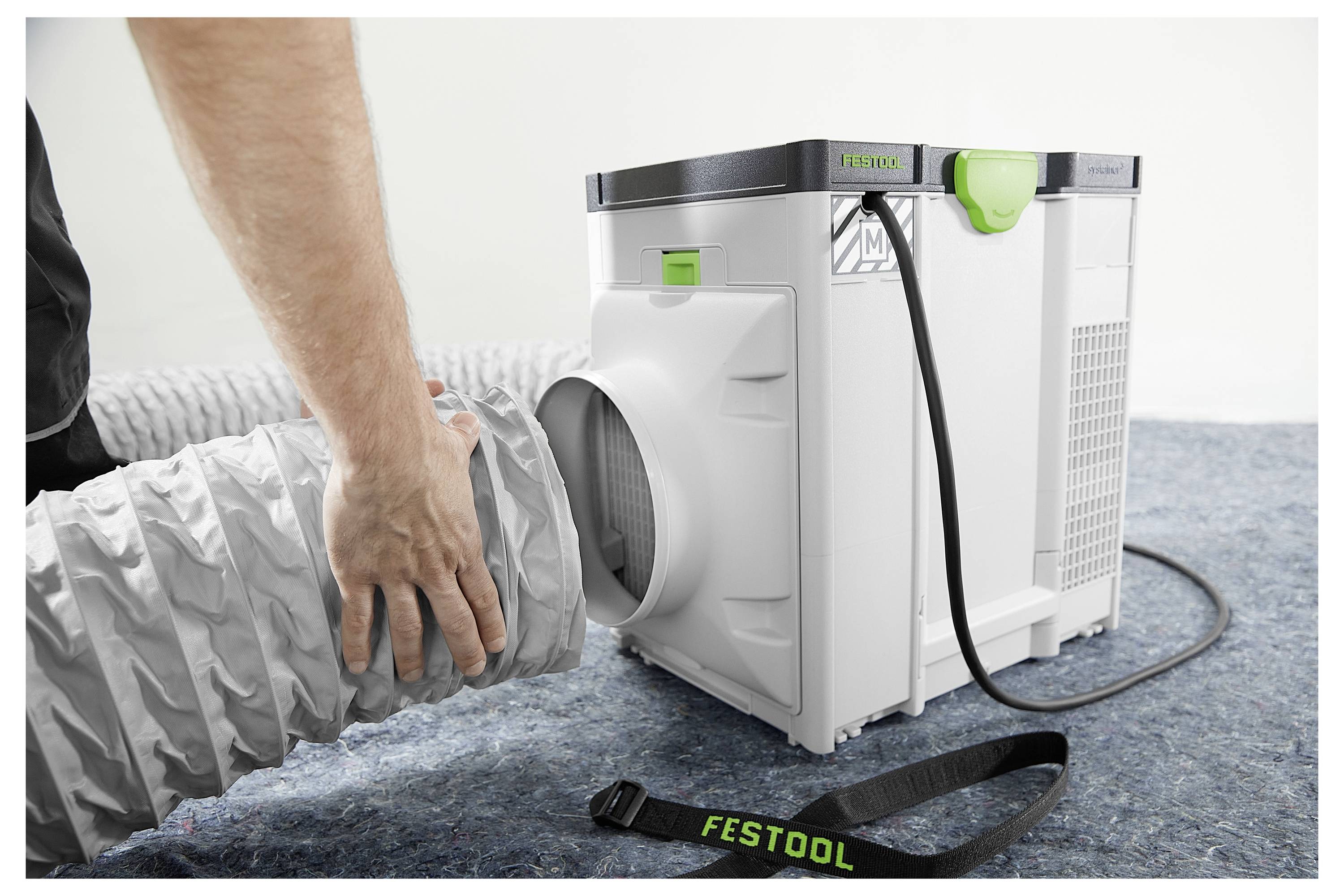 Eine Person mit Handschuhen wechselt das Sägeblatt einer Tischkreissäge aus und setzt ein kreisrundes Blatt auf den Tisch der Säge. Die Szene spielt sich in einer Werkstatt ab.