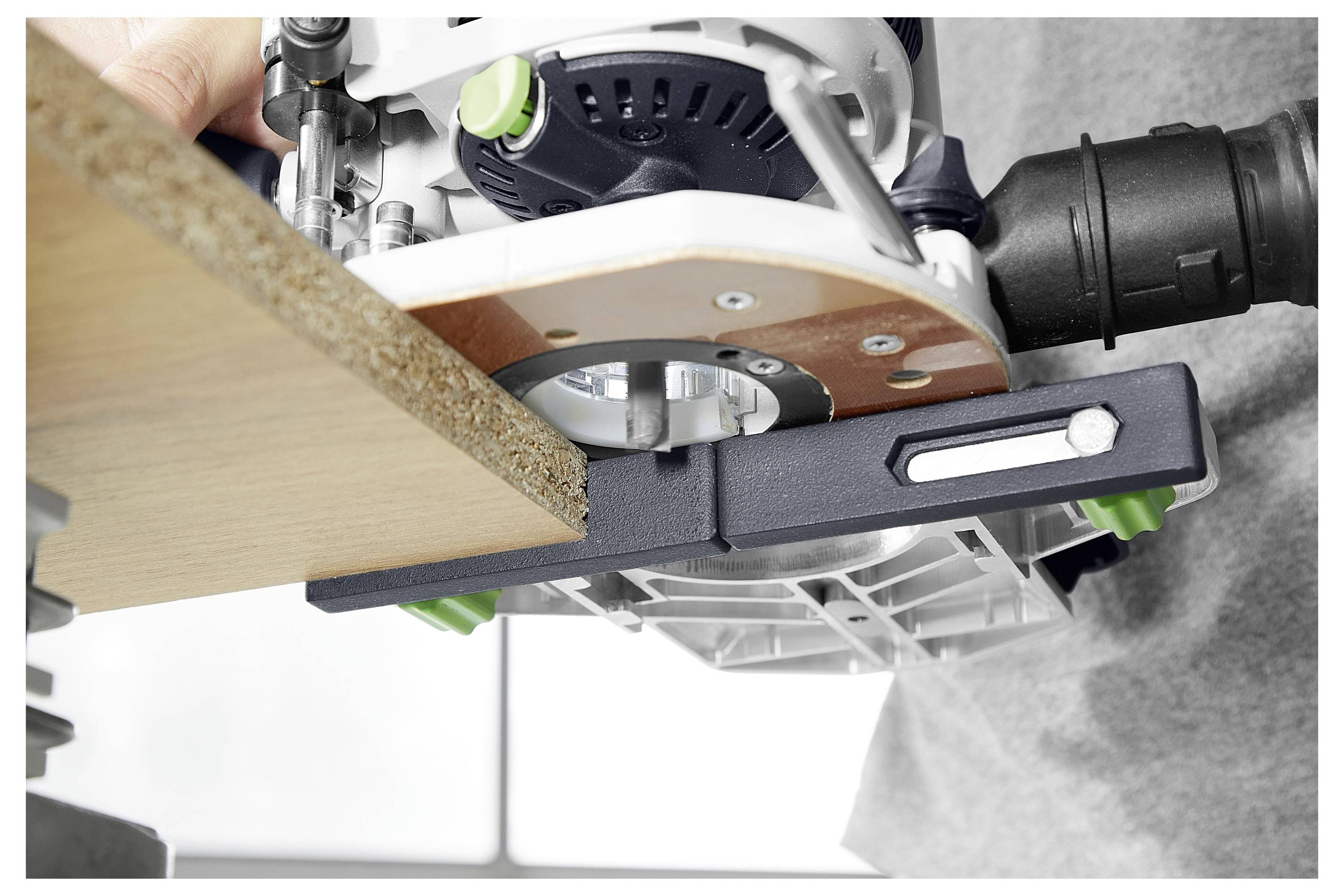 Eine Hand bedient einen Holzfräser an einer Kante eines Holzbretts und zeigt Präzision beim Trimmen oder Formen von Holz.