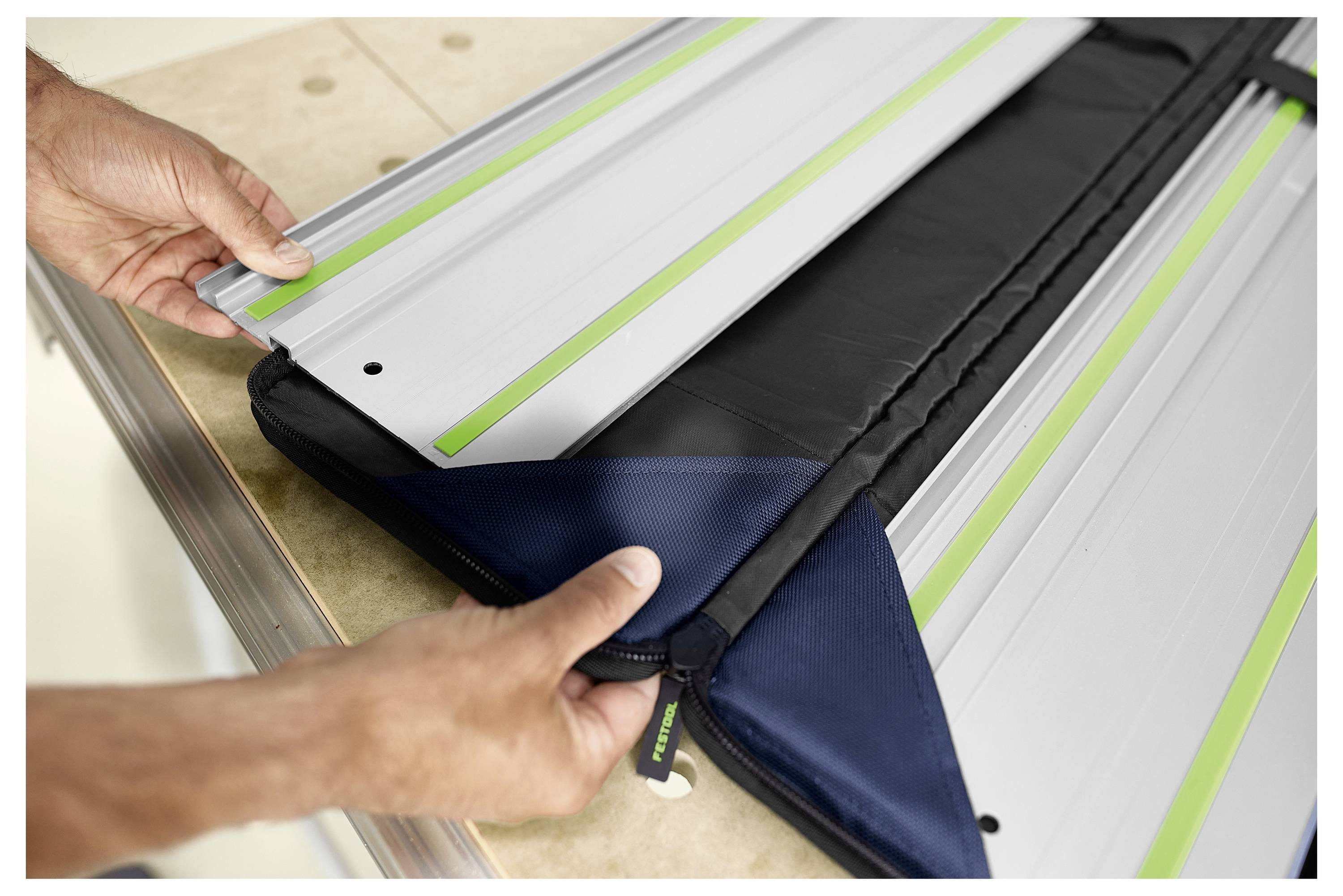 Eine Person mit grauem Haar lächelt, während sie ein Werkzeug in einer Werkstatt voller Holzbretter und Schreinerwerkzeuge verwendet.