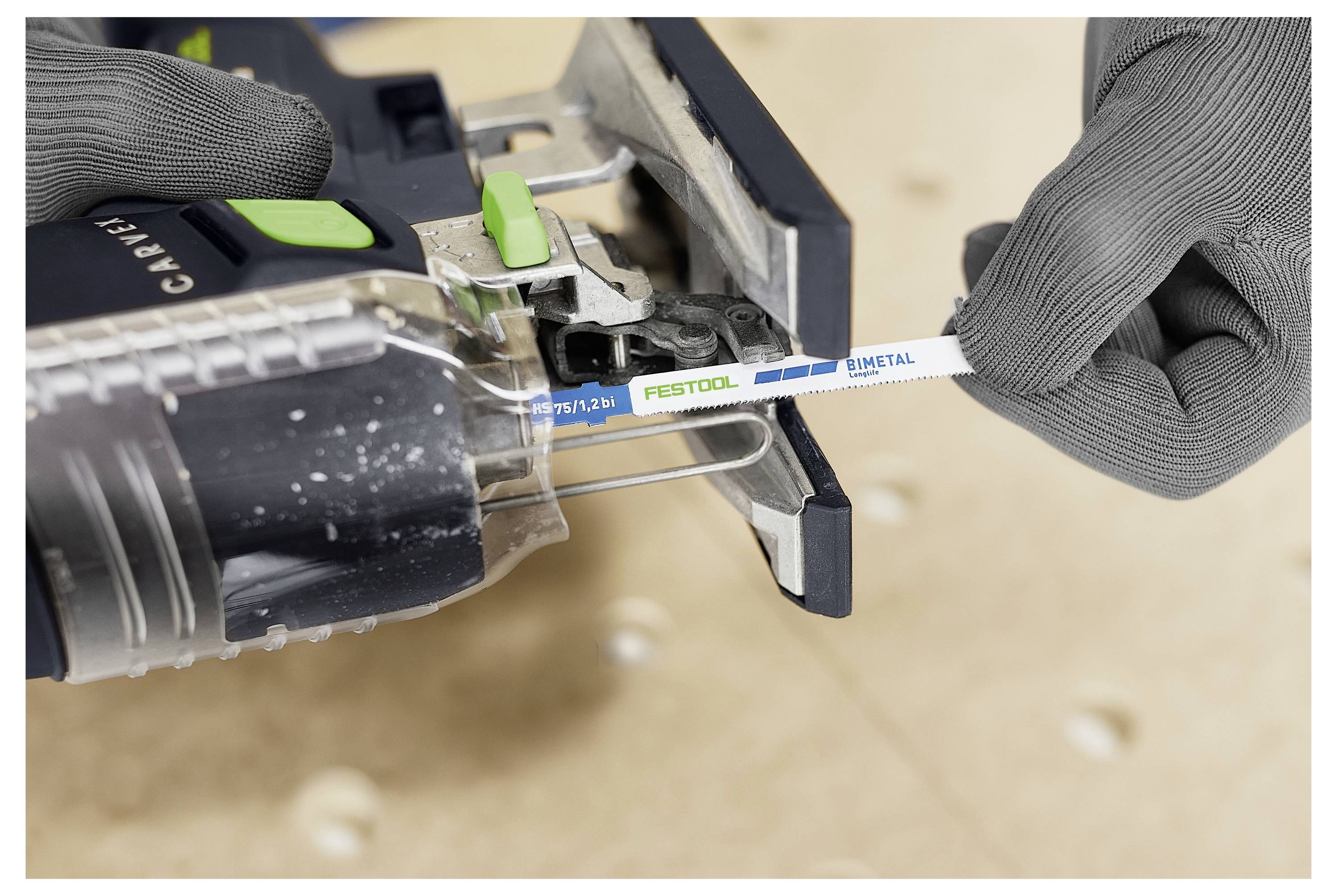 A person wearing gloves inserts a Festool saw blade labeled 'Metal' into a jigsaw tool, showing tool handling and blade setup.