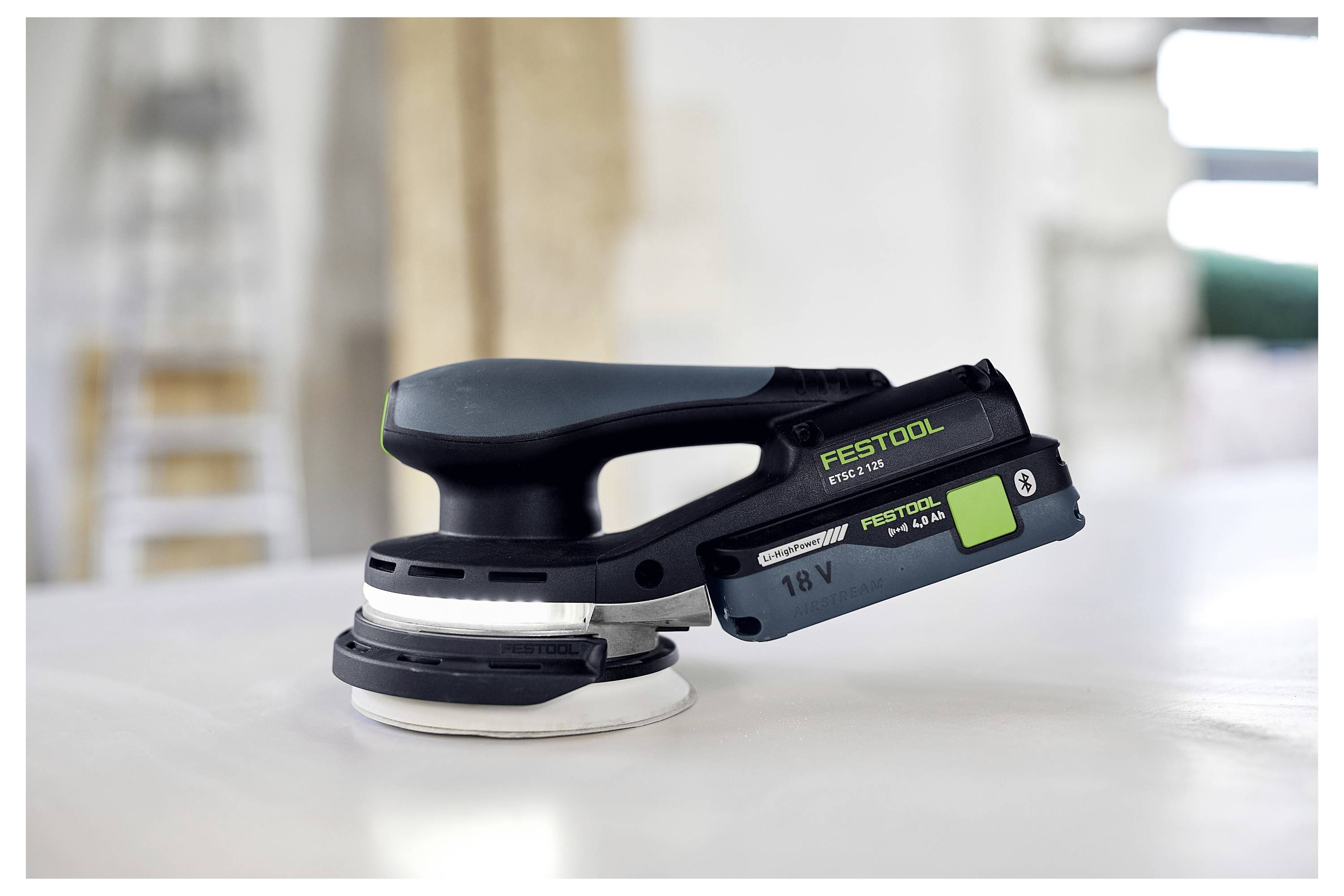 Eine Person, die eine Schutzbrille und einen Gehörschutz trägt, verwendet einen Elektroschrauber, um ein Loch in ein Holzbrett zu bohren und konzentriert sich intensiv auf die Aufgabe.