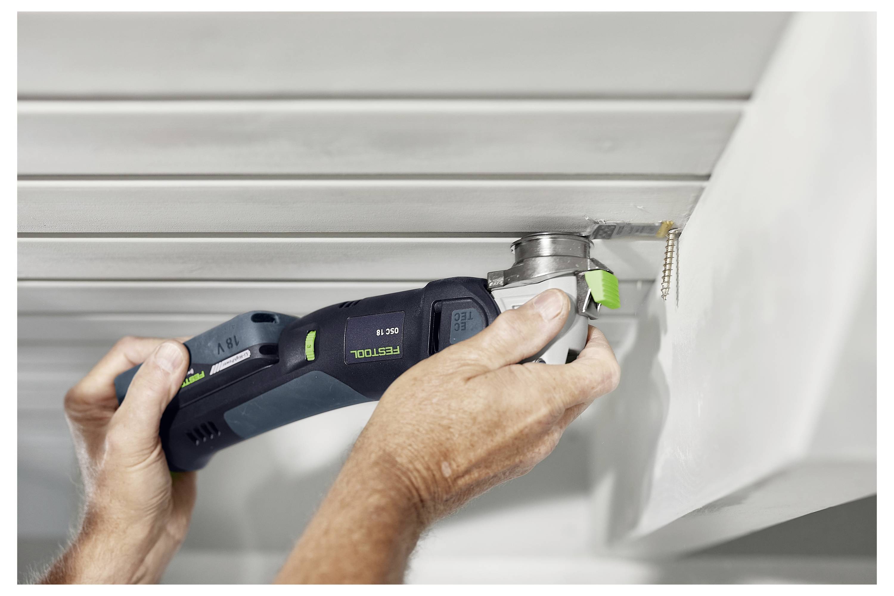 A person uses a power tool to cut a precise section of a wooden panel.