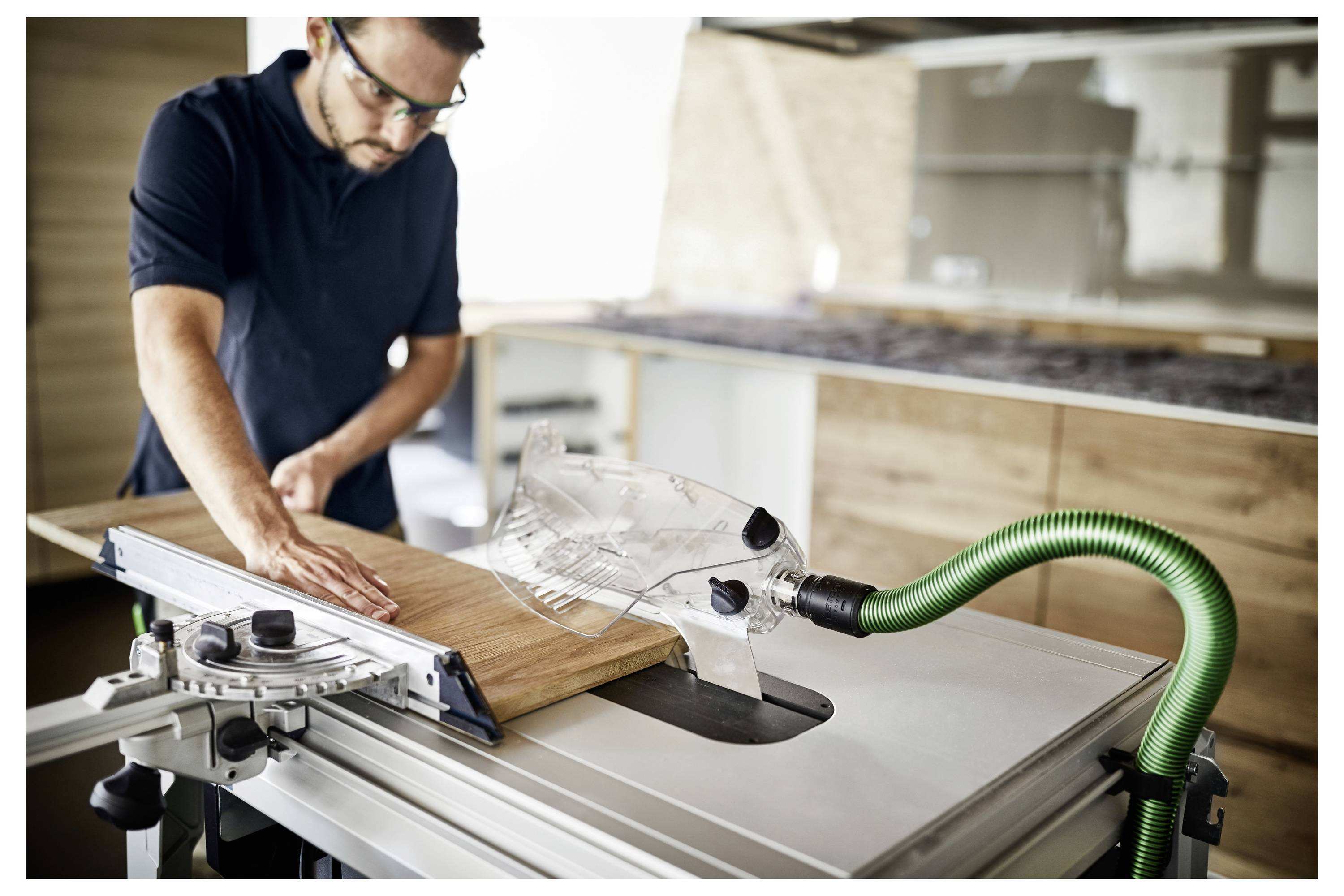 Ein Festool OF 1010 EBQ-Plus Oberfräser wird an einem Holzwerkstück verwendet, wobei präzise Schnitte entlang einer Führungsschiene durchgeführt werden, eingestellt in einer Werkstattumgebung.