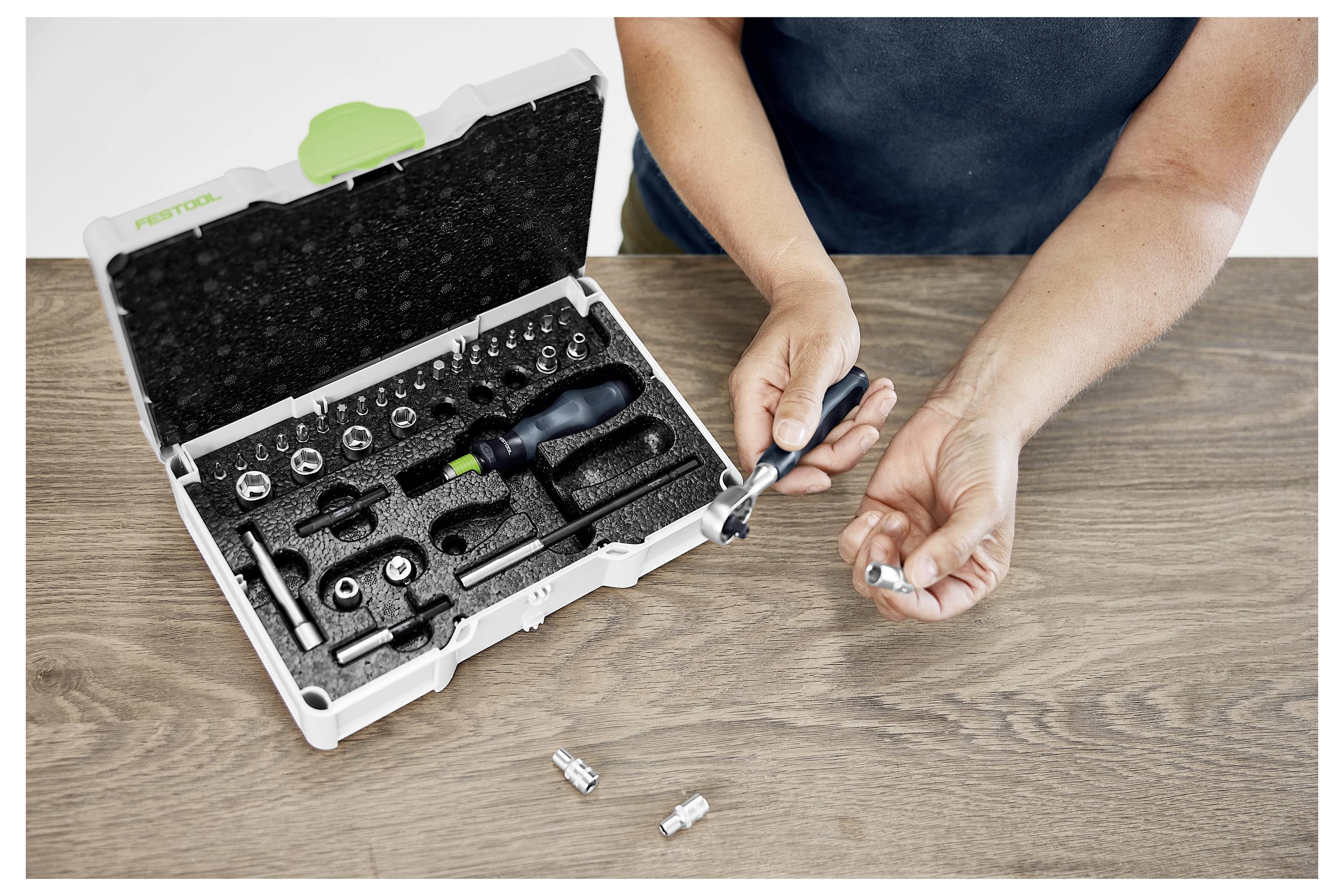 Ein Mann mit einer Schutzbrille benutzt ein Elektrowerkzeug, um an Fensterrahmen in einer hellen Werkstatt zu arbeiten.