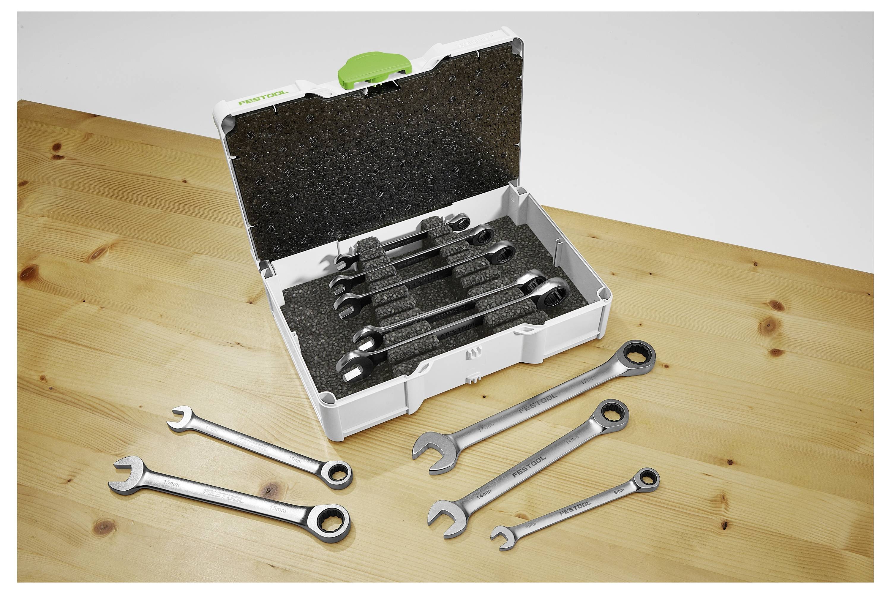 Ein Satz Schraubenschlüssel, die in einem Koffer mit Schaumstoffauskleidung organisiert sind, mit mehreren Schraubenschlüsseln, die auf einer Holzoberfläche daneben ausgelegt sind.