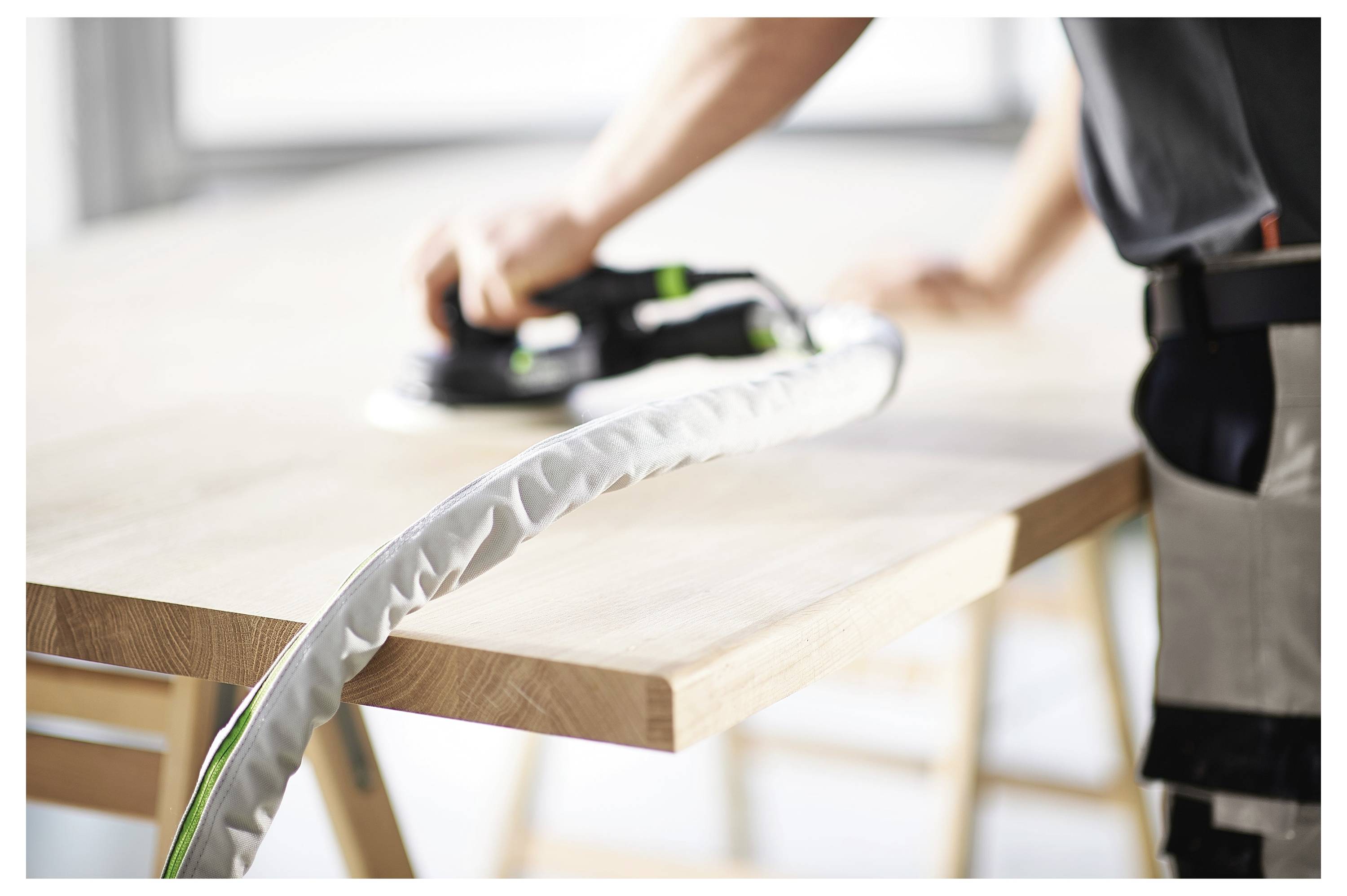 Eine Person, die Handschuhe trägt, montiert eine Kreissäge auf einem Holztisch zusammen, wobei Werkzeuge und Komponenten in der Nähe sind und Sicherheit sowie Präzision betont werden.