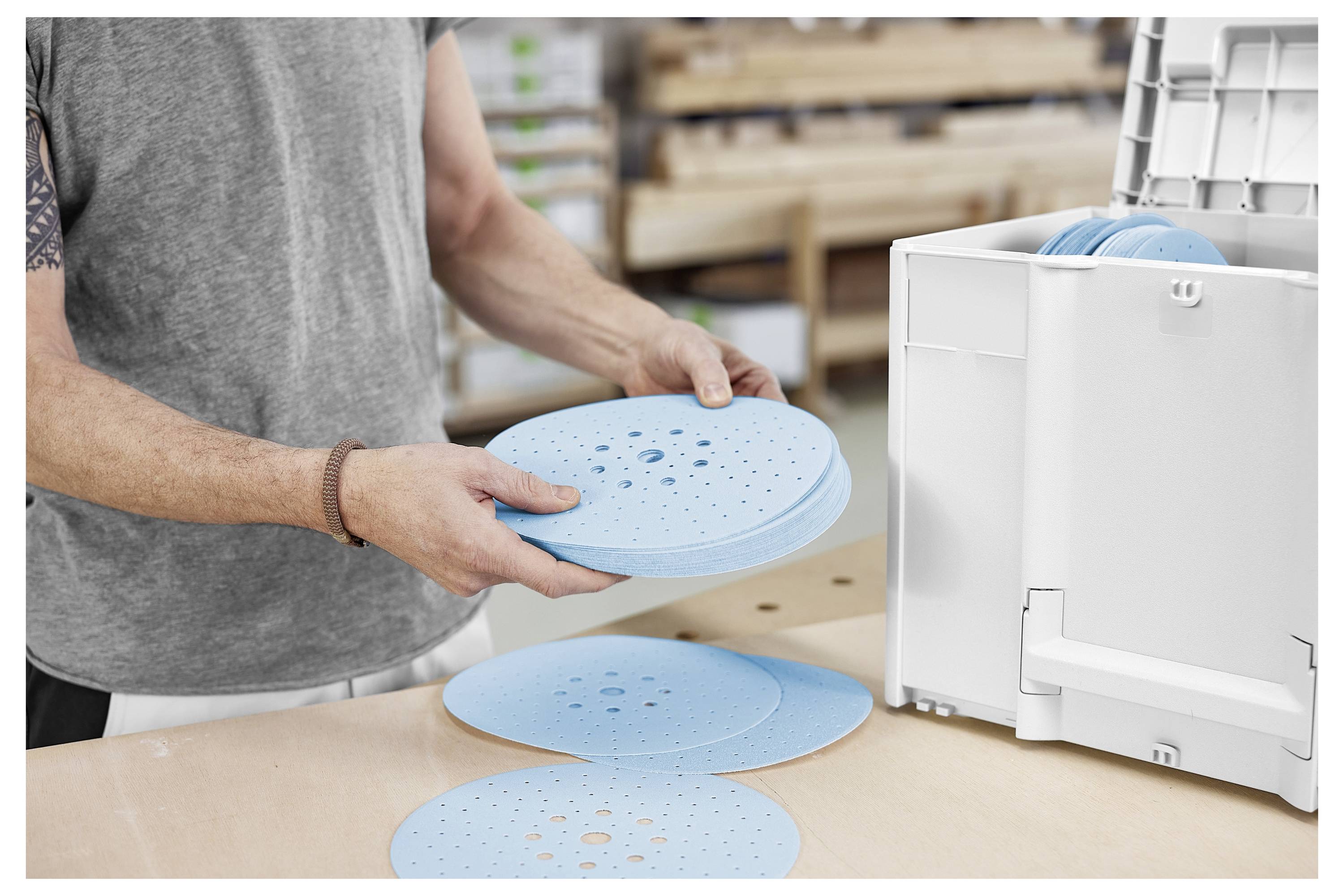 Eine Person nutzt ein Holzbearbeitungswerkzeug, um präzise Schlitze in Holzbalken auf einer Werkbank zu schneiden und demonstriert dabei Holzbearbeitungspräzision und Technik.