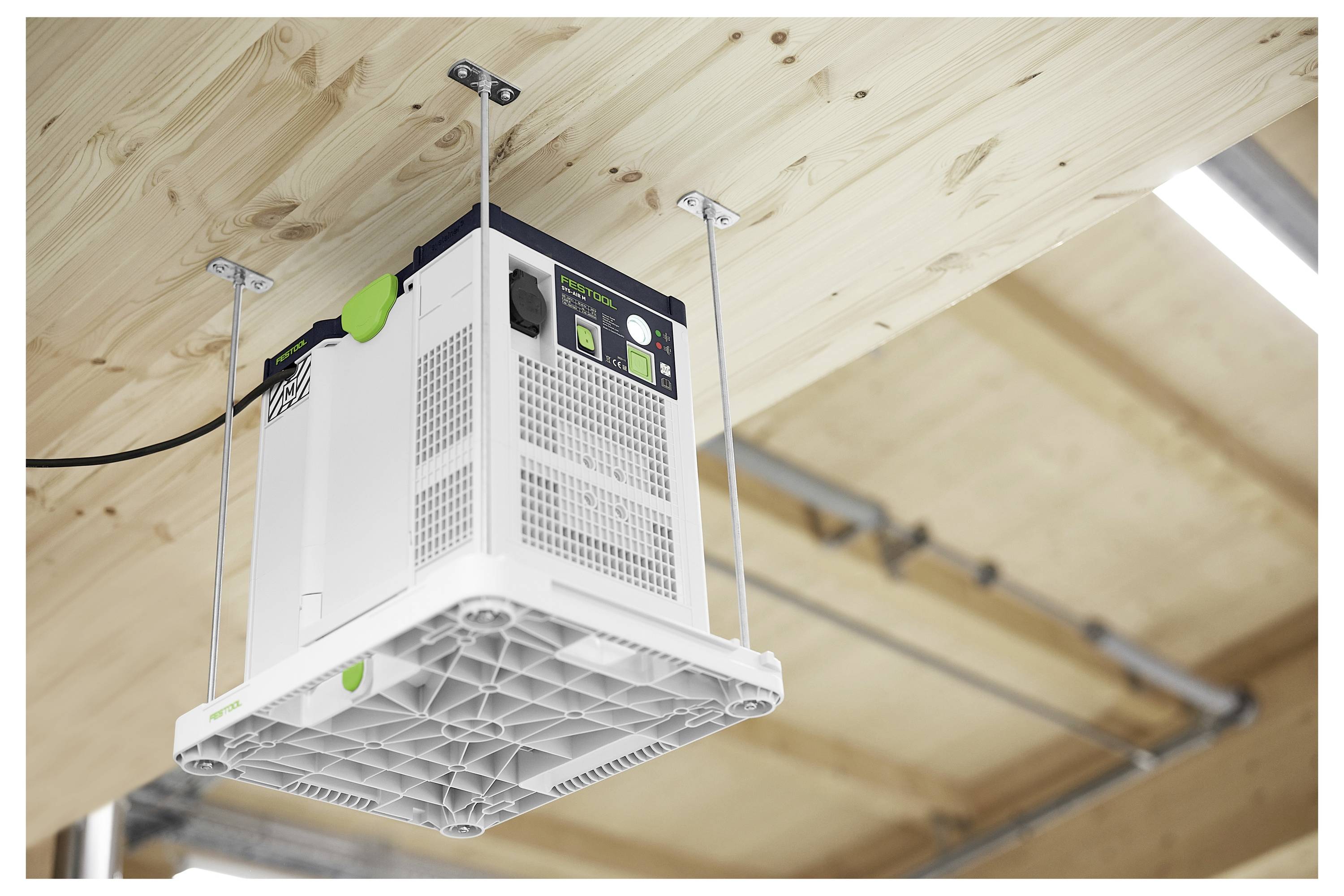 Ein weißes Luftfilterungsgerät ist mit Metallklammern verkehrt herum an einer hölzernen Decke in einer Werkstattumgebung befestigt.