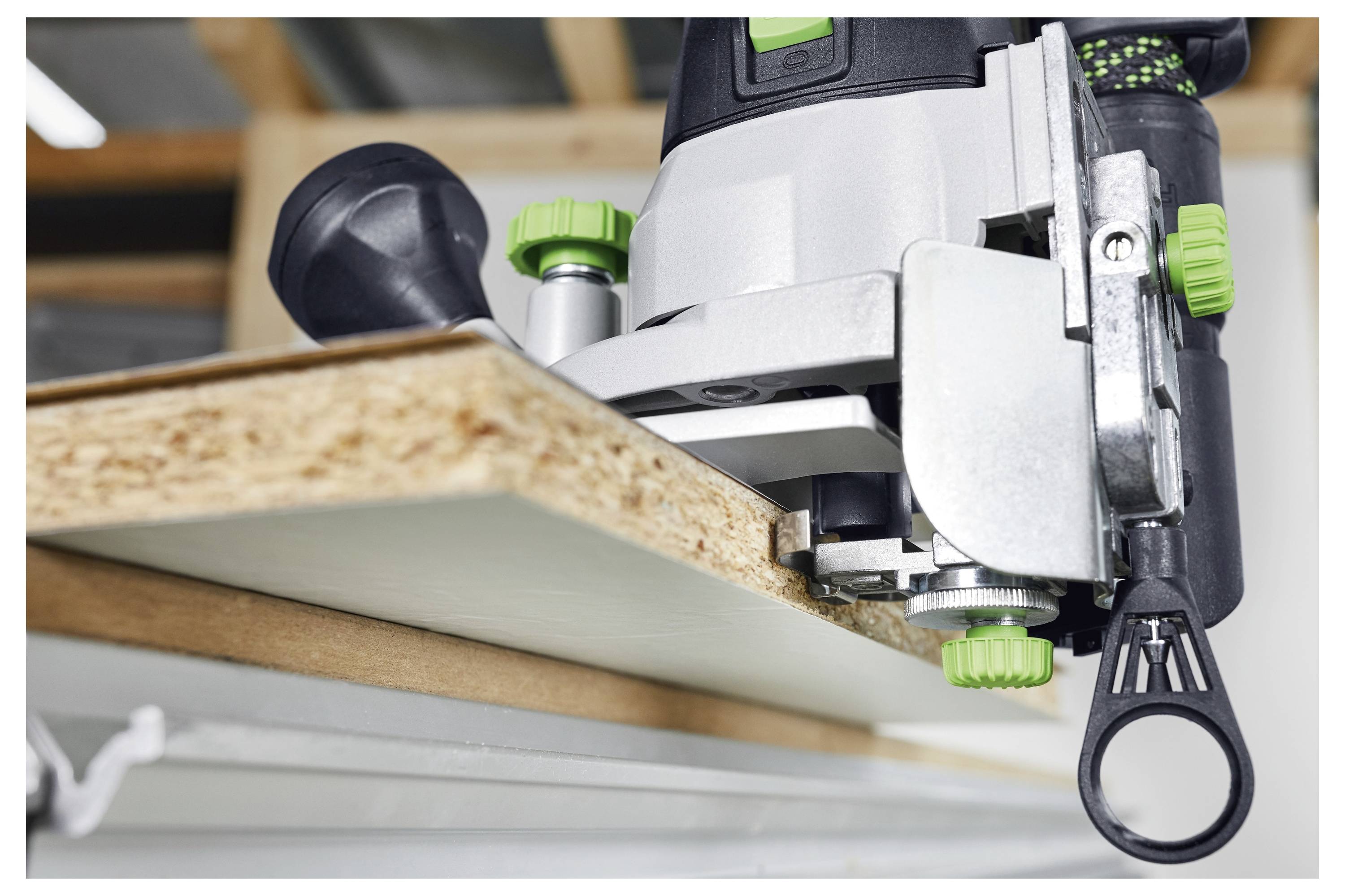 Eine Nahaufnahme eines Elektrowerkzeugs, das die Kante eines Holzbretts trimmt, zeigt Präzisionsarbeit in einer Werkstattumgebung.
