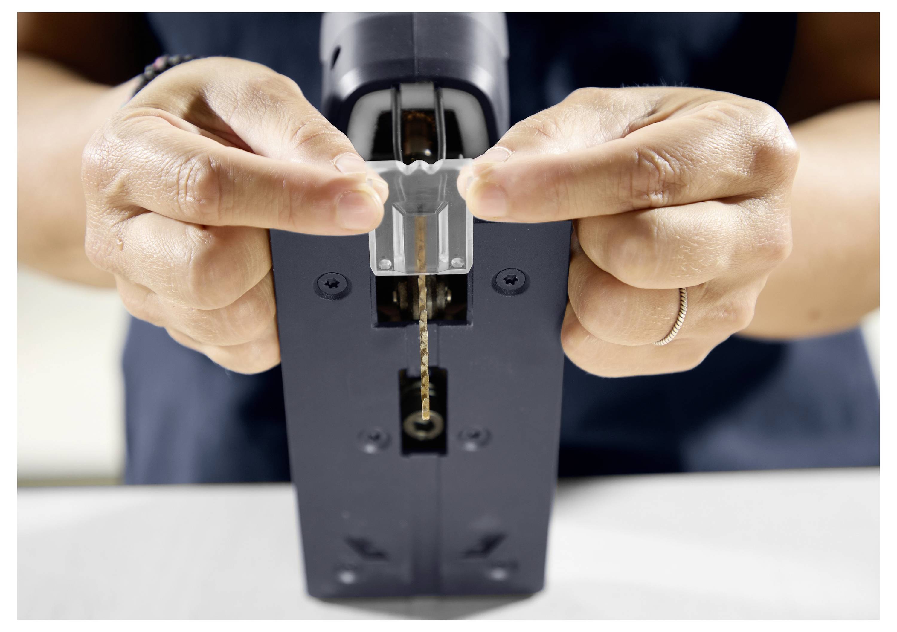 Eine Person trägt Schutzbrille und Handschuhe und bedient ein Festool-Elektrowerkzeug, wobei sie sich intensiv auf die Aufgabe konzentriert.