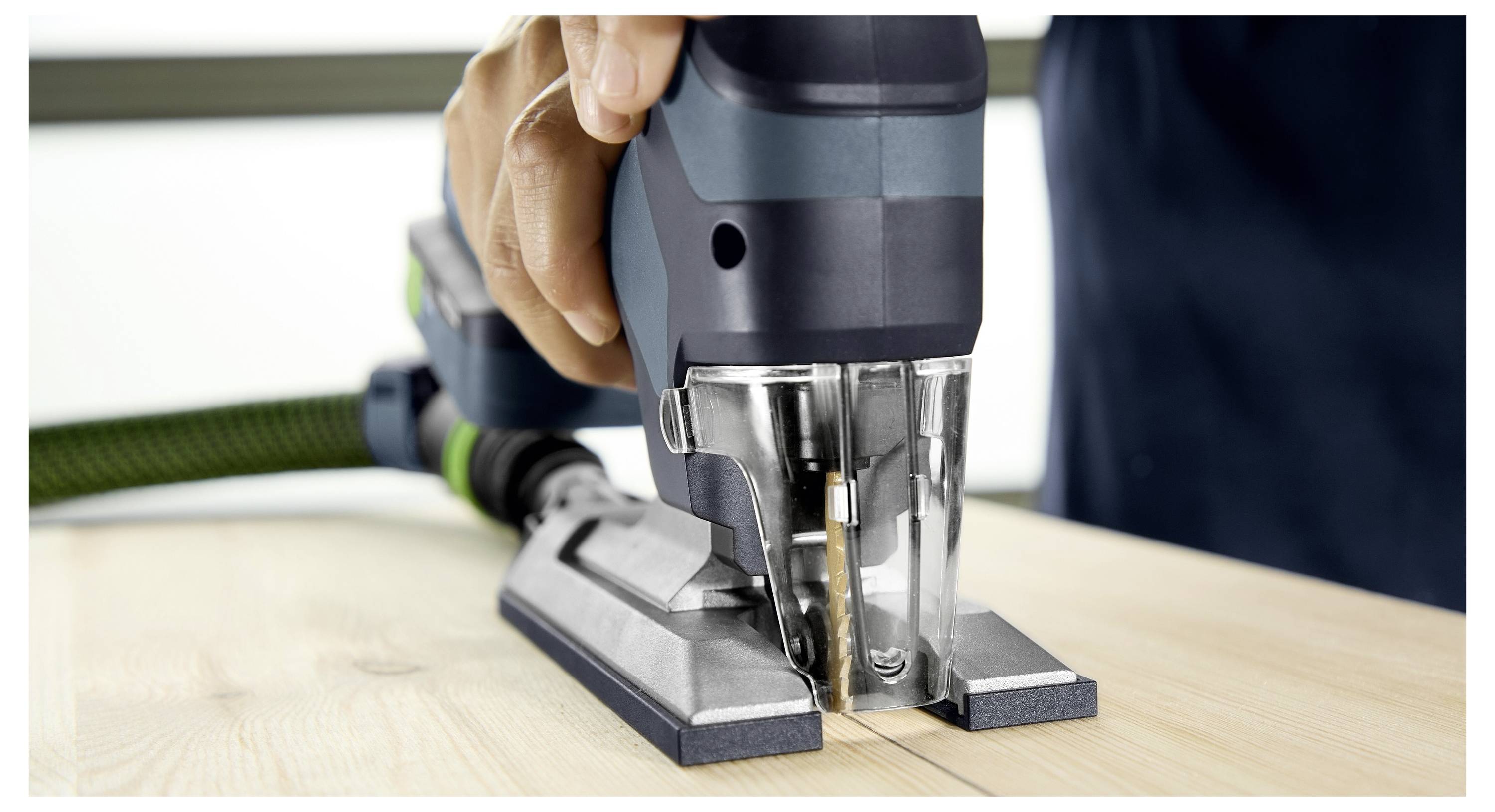 Eine Person benutzt eine elektrische Stichsäge, um Holz zu schneiden, wobei der Fokus auf dem Werkzeug in Aktion liegt.
