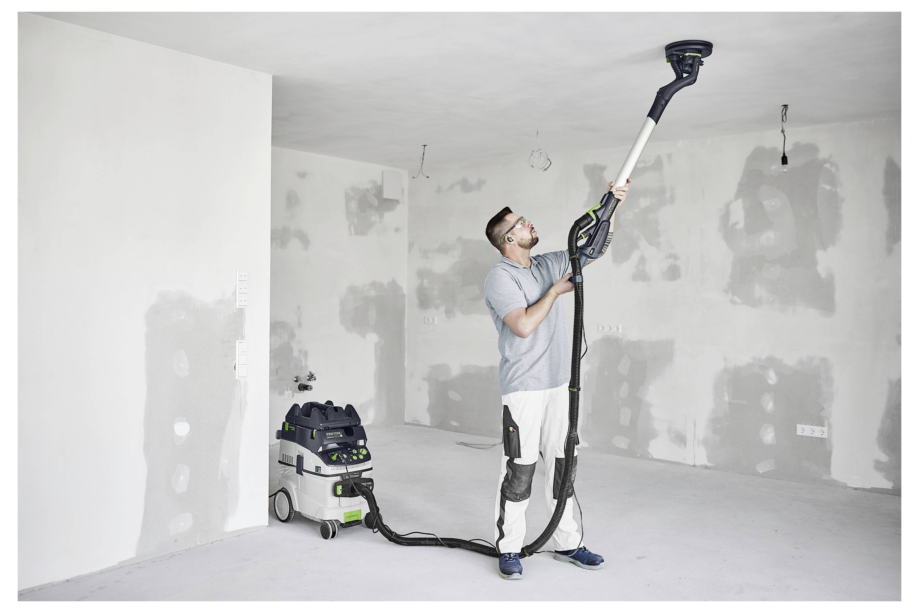 Ein Mann mit einer Schutzbrille benutzt eine Kreissäge, um Holz auf einer Werkbank in einer Werkstatt zu schneiden.