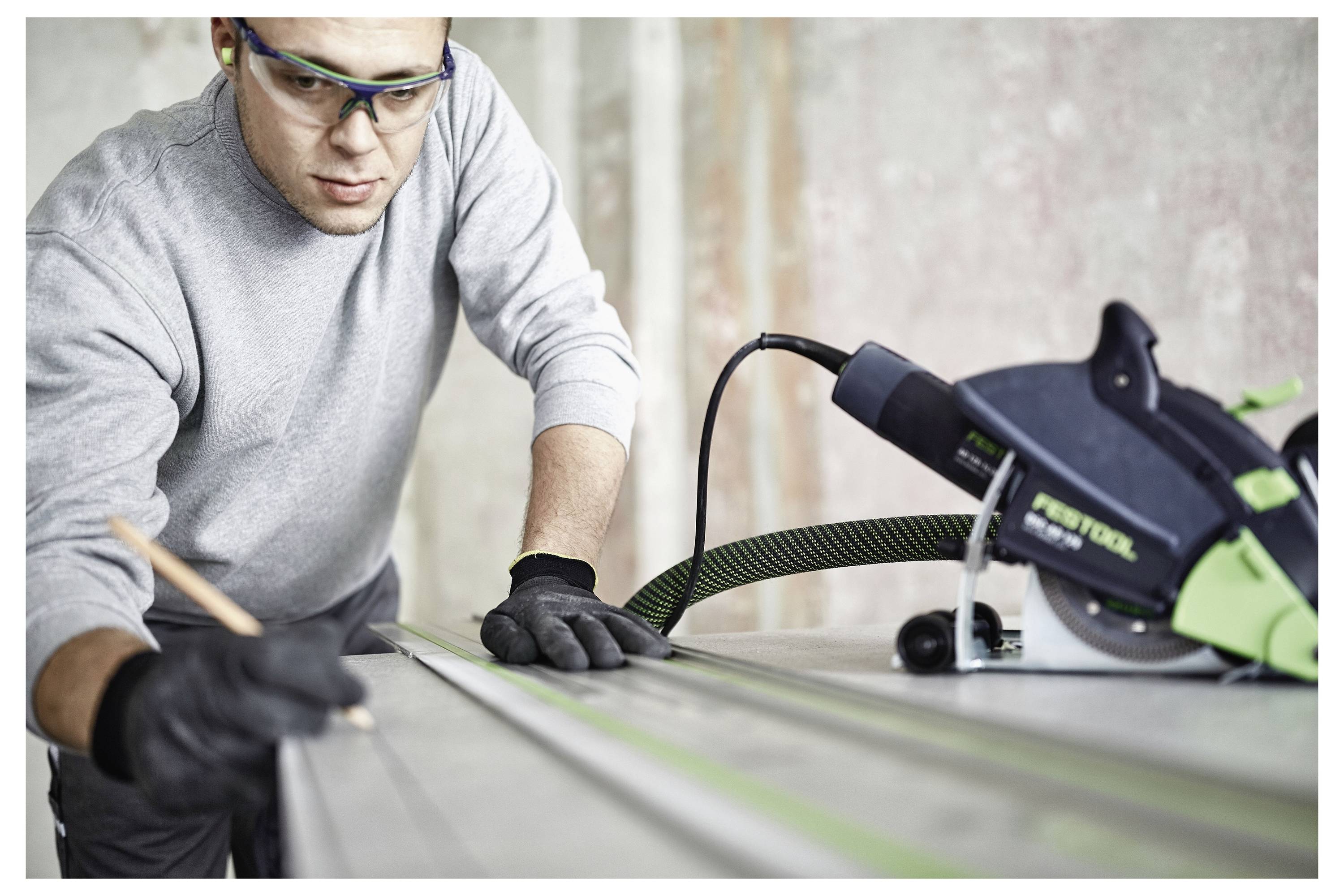 Eine Person nutzt ein Holzbearbeitungswerkzeug, um präzise Verbindungen in leichten Holzbalken herzustellen, was auf handwerkliche Geschicklichkeit und Liebe zum Detail hindeutet.