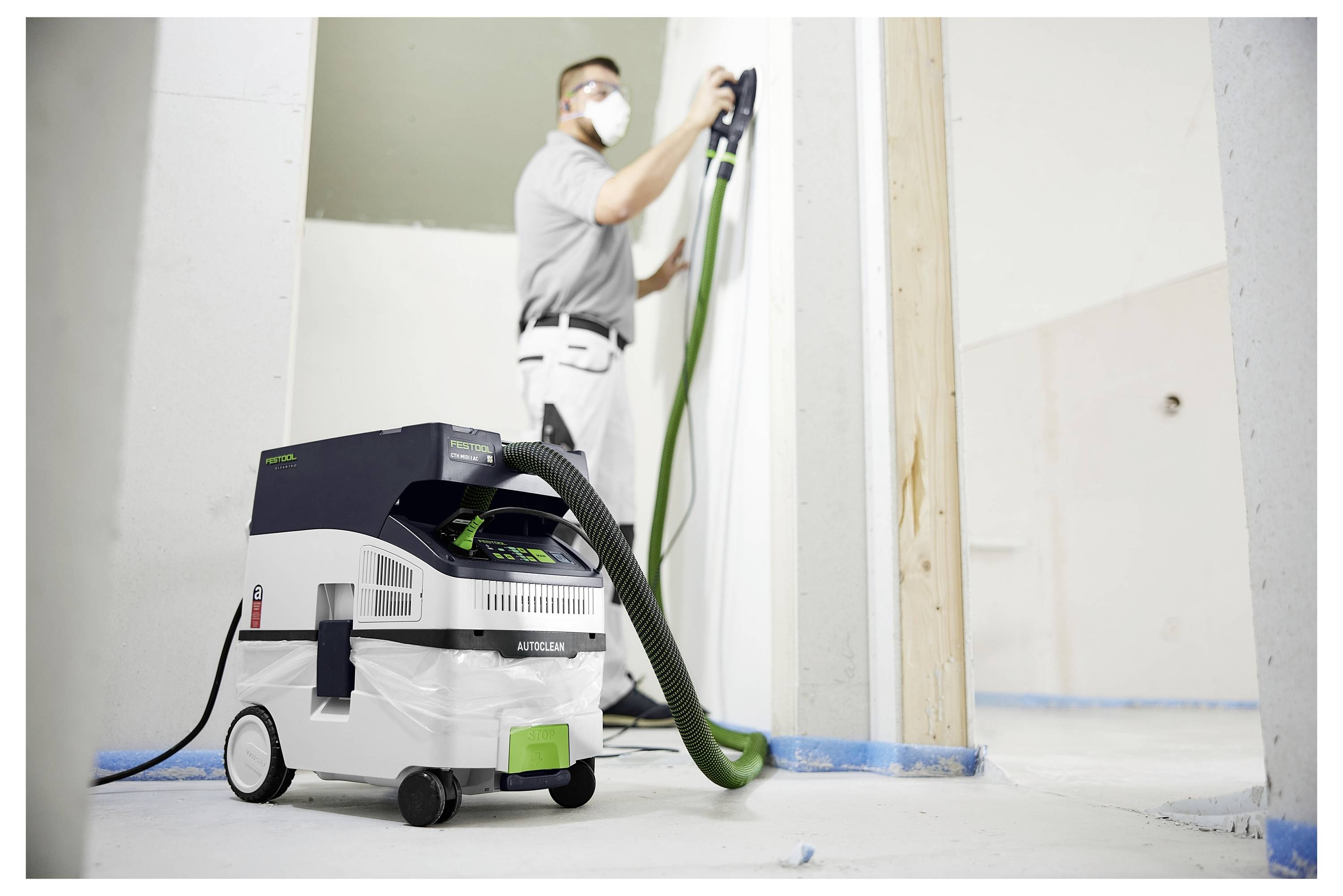 Eine Person in Handschuhen hält eine Kreissäge, mit zwei zusätzlichen Sägeblättern und einer Batterie auf einer Werkbank.