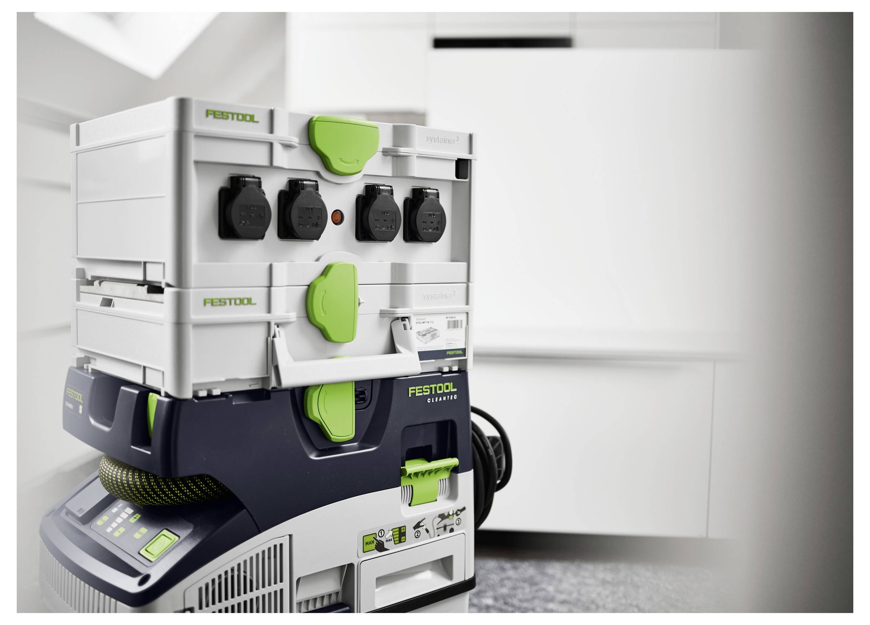 Eine Ladestation für mehrere Geräte mit Werkzeugen und Kabeln, die in einer weiß-grünen Einheit in einem modernen, minimalistischen Raum organisiert sind.