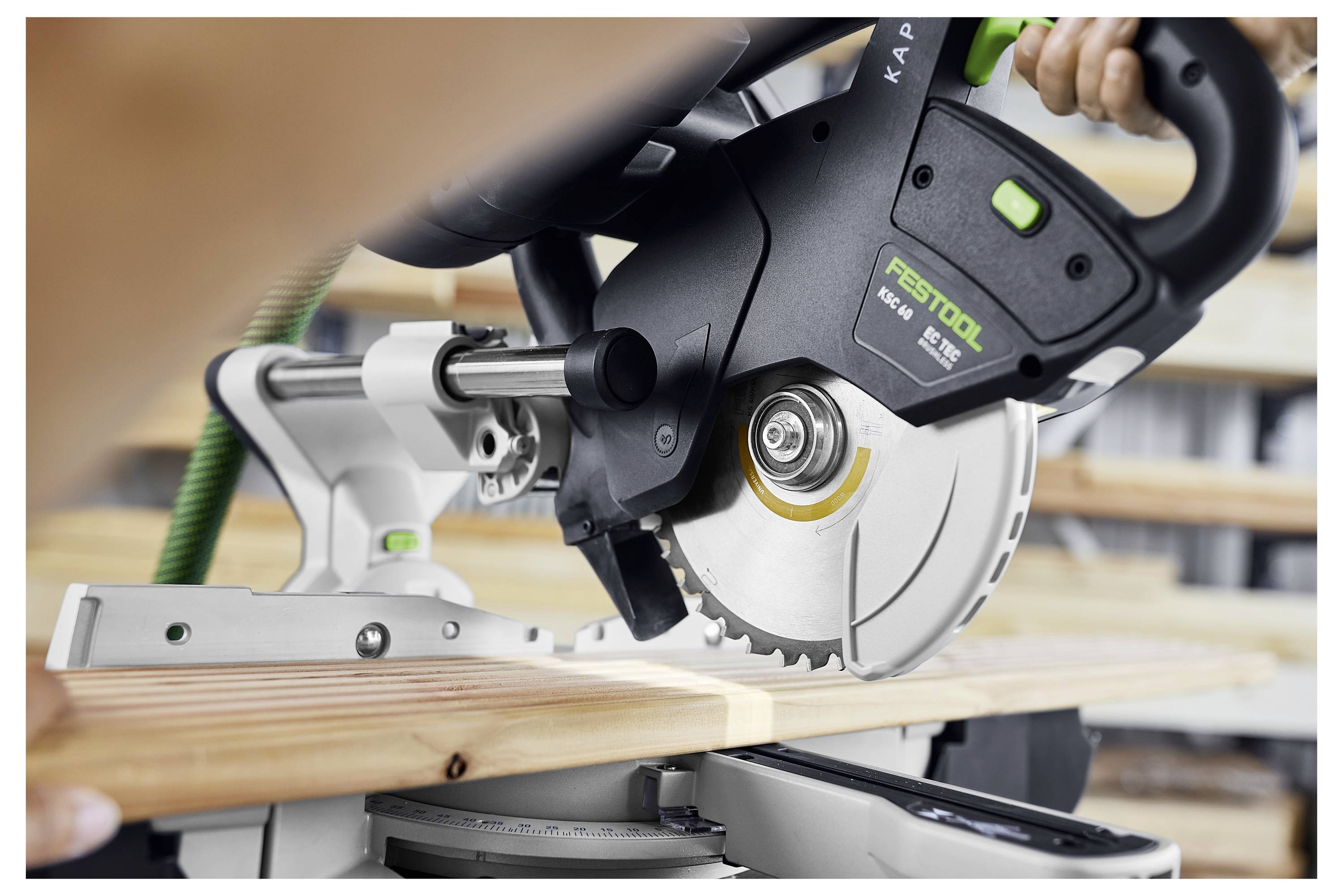 Eine Person in weißer Hose und blauen Sneakern bedient ein Festool-Werkzeug an einer Wand und glättet die Oberfläche über einem Teppichboden.