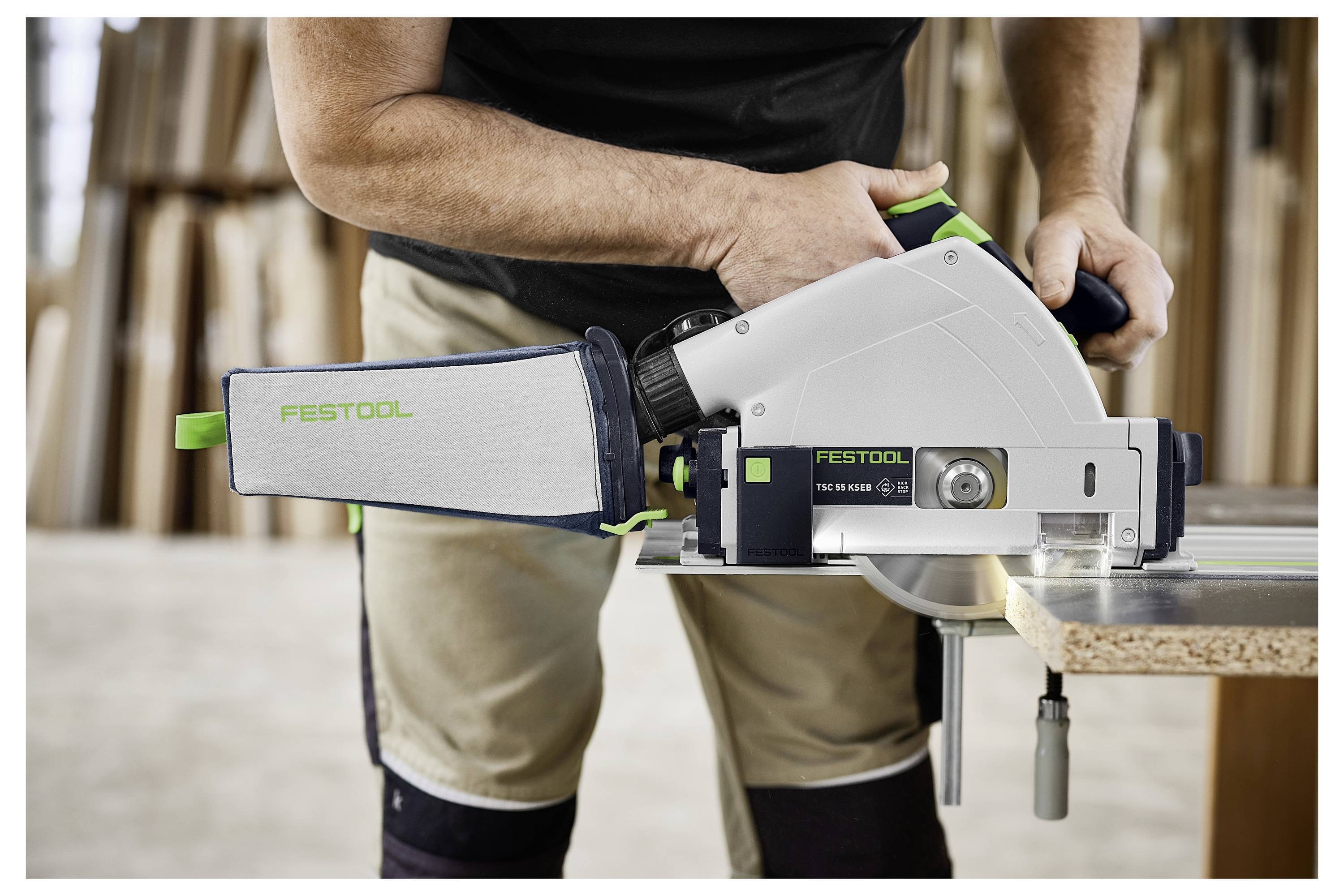 Eine Hand passt eine transparente Staubabsaugvorrichtung an einem auf einer Holzoberfläche platzierten Festool OF 1400 EBQ Oberfräser an und demonstriert damit die Werkzeugeinrichtung.