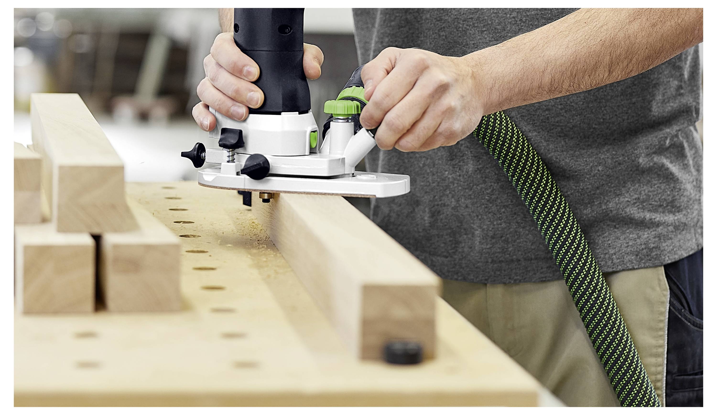 Eine Nahaufnahme eines Holzbearbeitungswerkzeugs, das die Kante eines Holzbretts trimmt und die Präzision des Schnitts entlang der Oberfläche des Bretts zeigt.