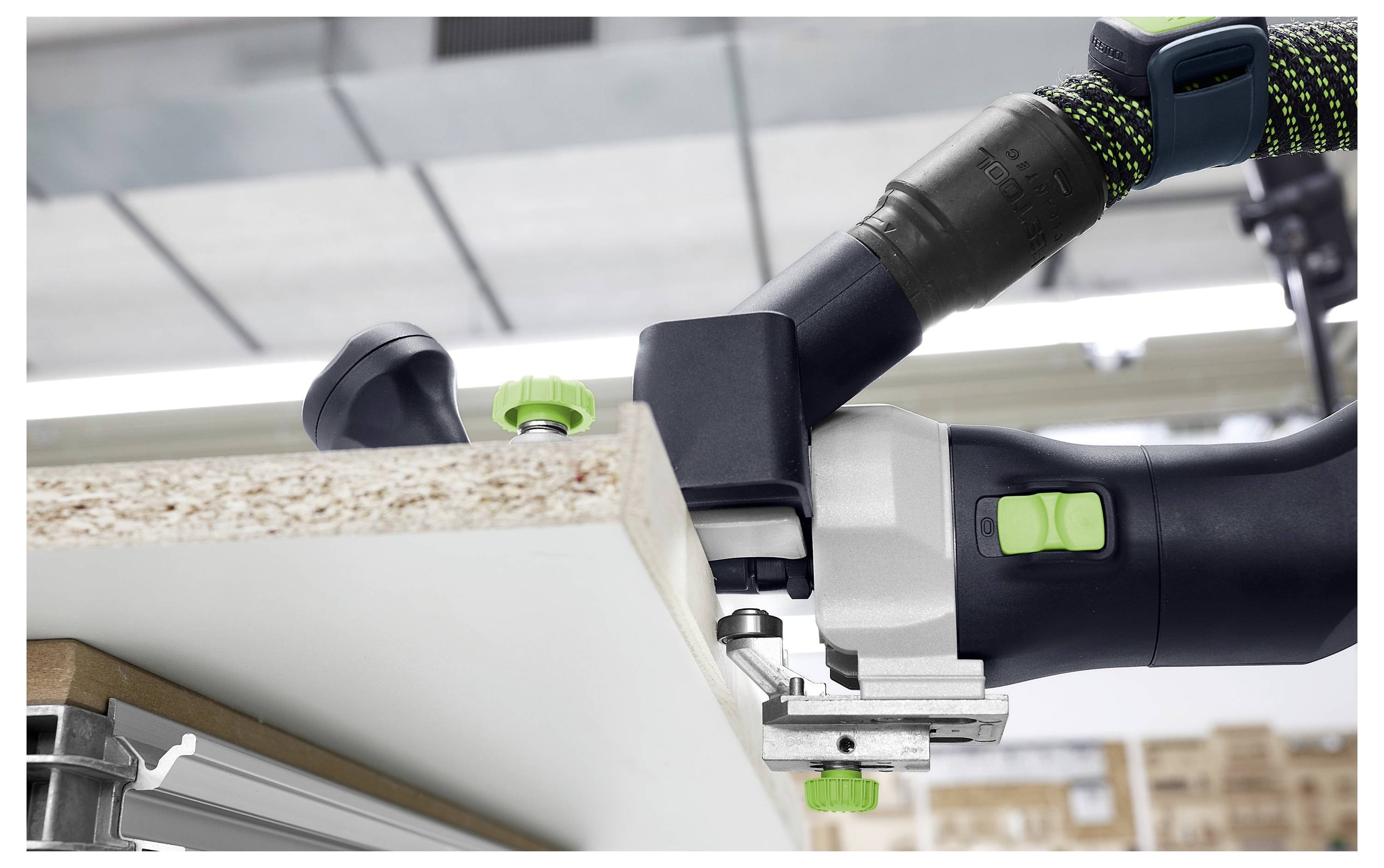 Eine Nahaufnahme einer Person, die ein Präzisions-Holzbearbeitungswerkzeug verwendet, um eine Nut in die Kante eines weißen Bretts in einer Werkstatt-Umgebung zu schneiden.