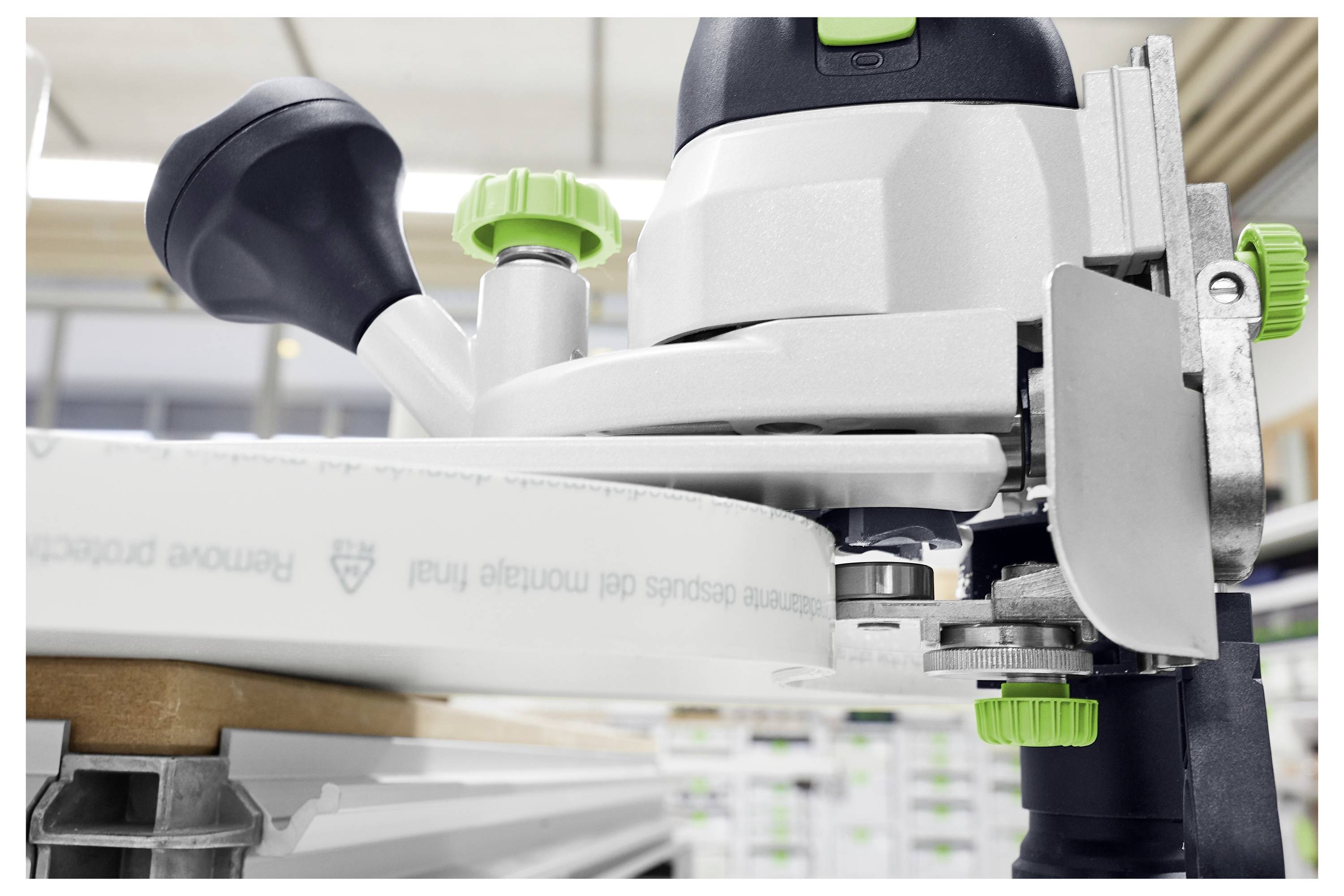 Eine Nahaufnahme einer Holzbearbeitungsfräsmaschine mit grünen Drehknöpfen, die sich auf ihren Präzisionsmechanismus konzentriert, in einer Werkstattumgebung.