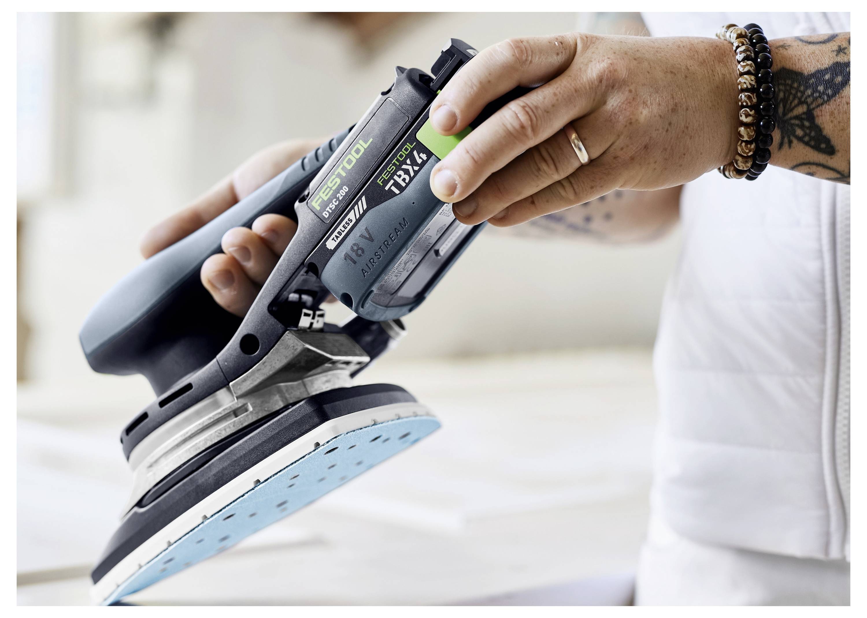 Eine Person wählt eine kreisförmige Schleifscheibe aus einem Lagerfach mit Kartons ähnlicher Scheiben aus, was auf die Vorbereitung einer Aufgabe hindeutet.