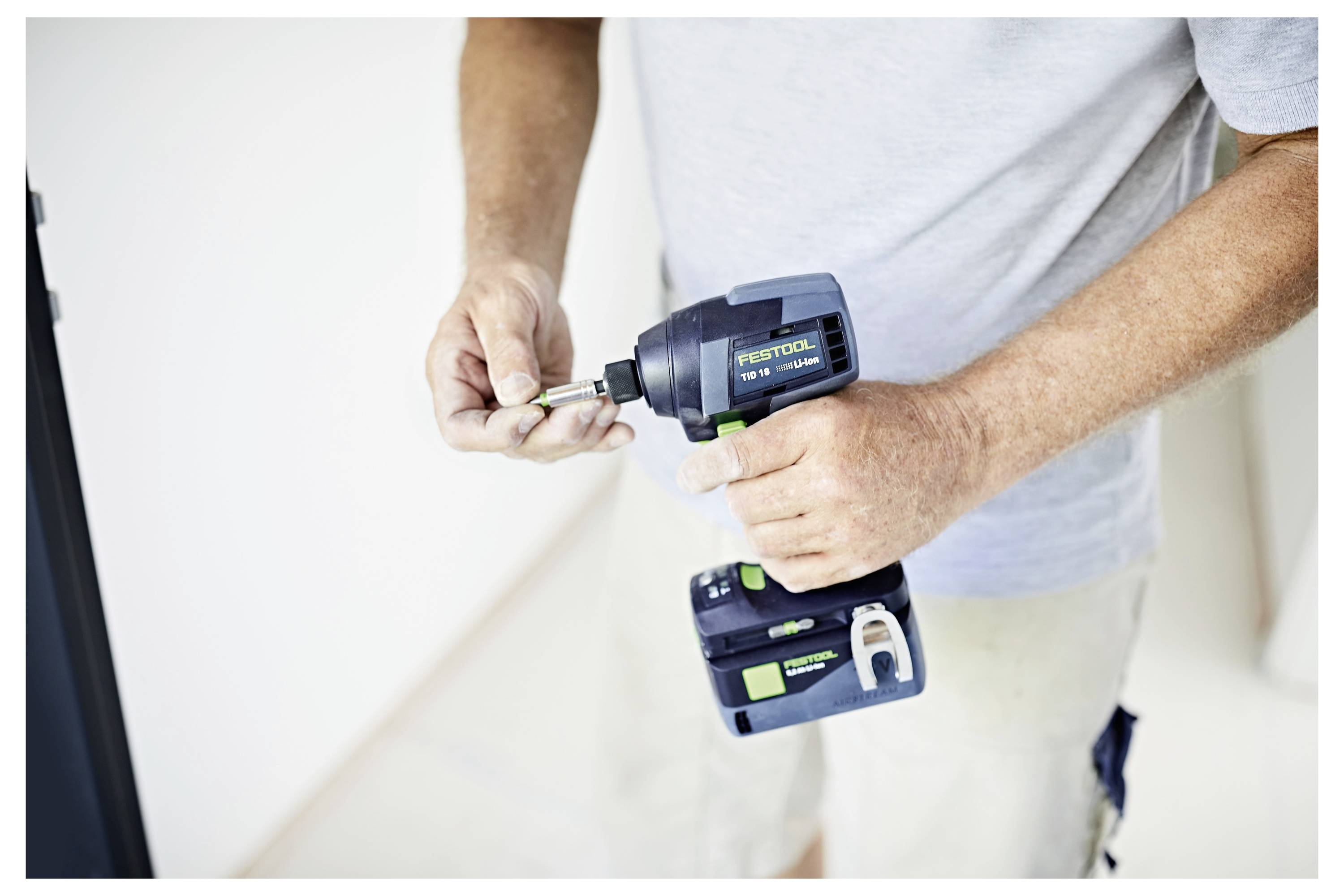 Eine Person verwendet eine Festool Elektrobohrmaschine und bereitet sich darauf vor, einen Bohraufsatz anzubringen. Das Bild konzentriert sich auf das Werkzeug und die Hände im Kontext eines DIY-Projekts.