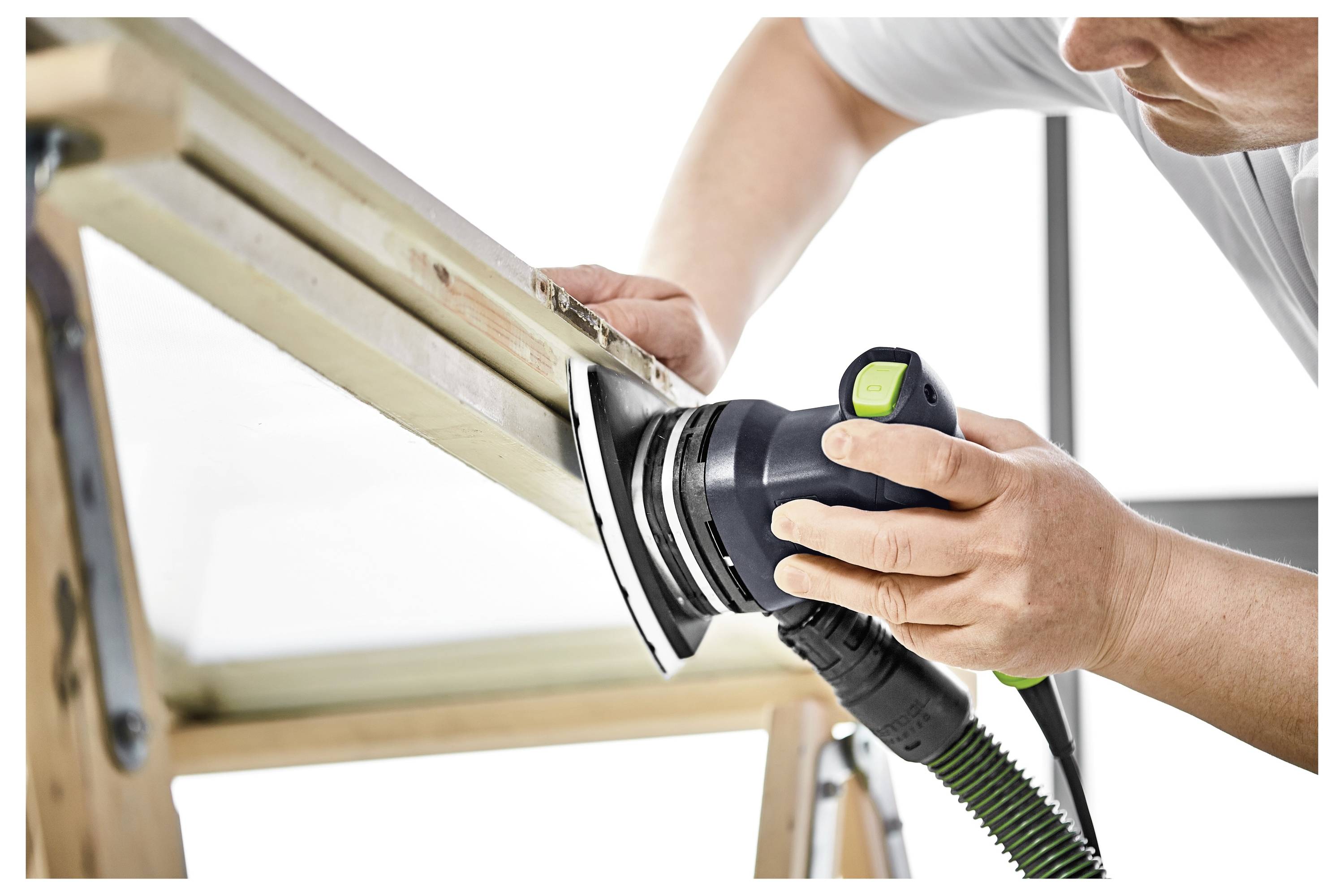 Eine Person verwendet einen Elektroschleifers, um die Oberfläche eines auf einer Werkbank gehaltenen Holzbretts zu glätten.