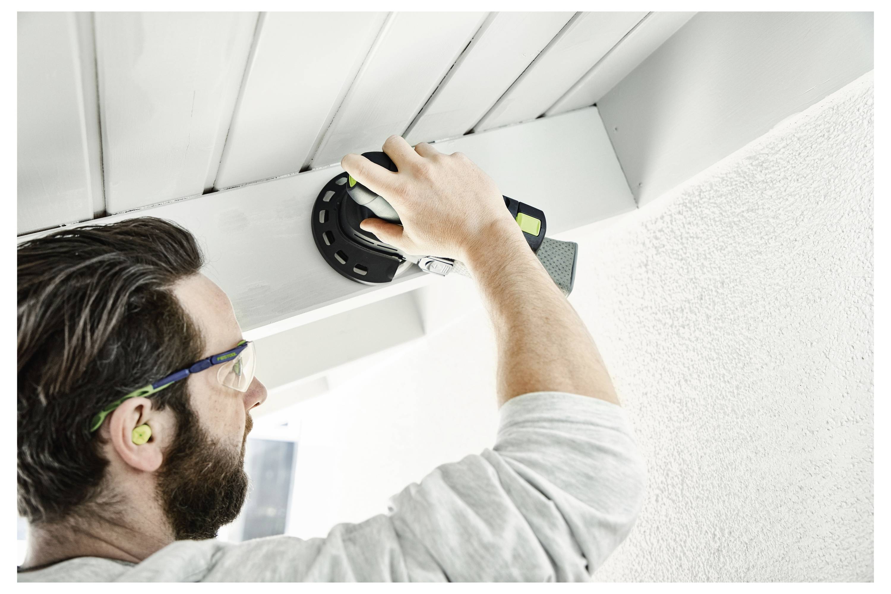 Person, der einen elektrischen Schleiffer auf einer Holzoberfläche bedient, demonstriert die richtige Handpositionierung für die Werkzeugbenutzung und -kontrolle.