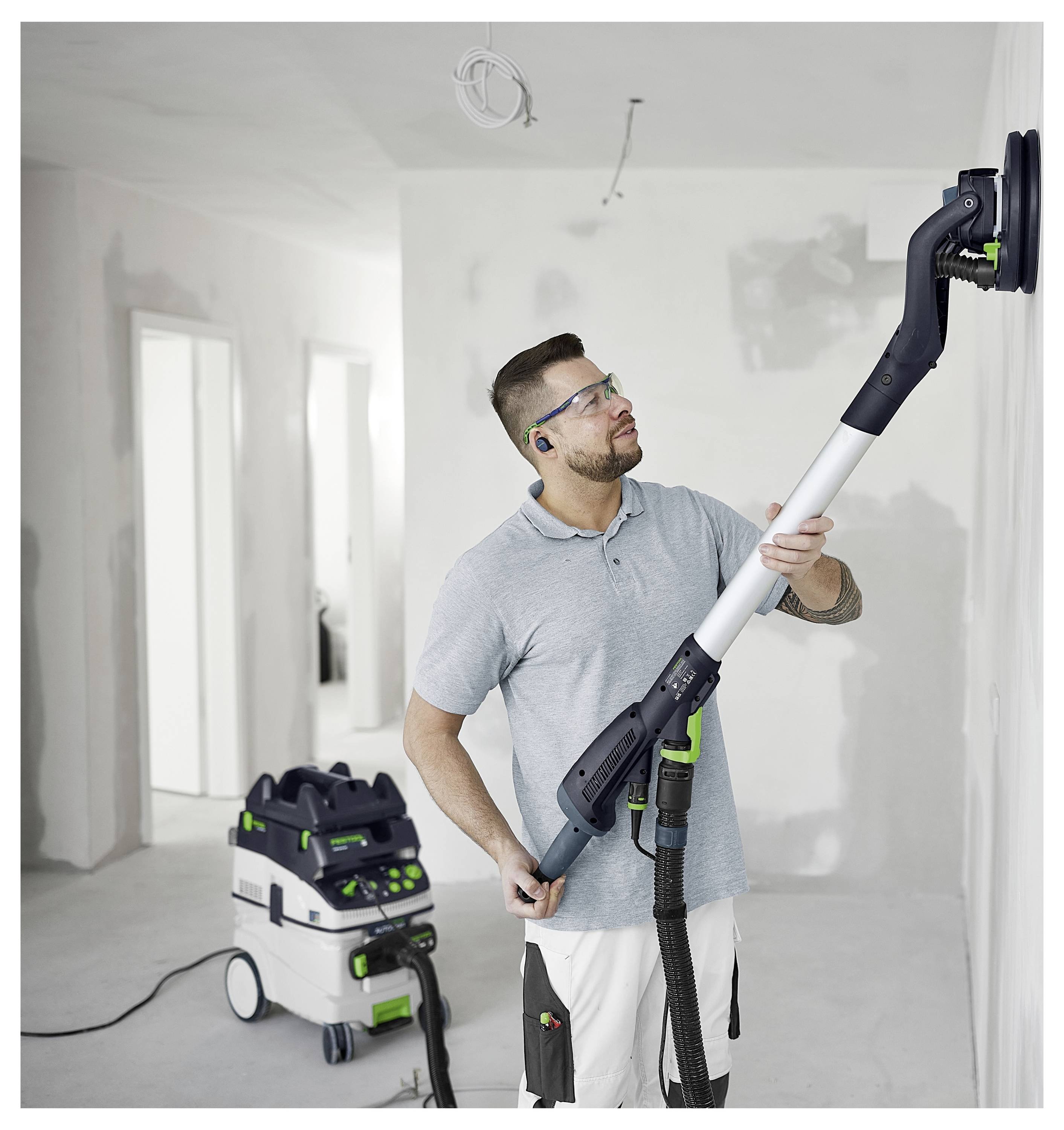 Eine Hand benutzt einen Festool-Schleifer auf einer ebenen Fläche und zeigt sein ergonomisches Design und Kontrollfunktionen, wobei die Präzision bei Schleifaufgaben betont wird.