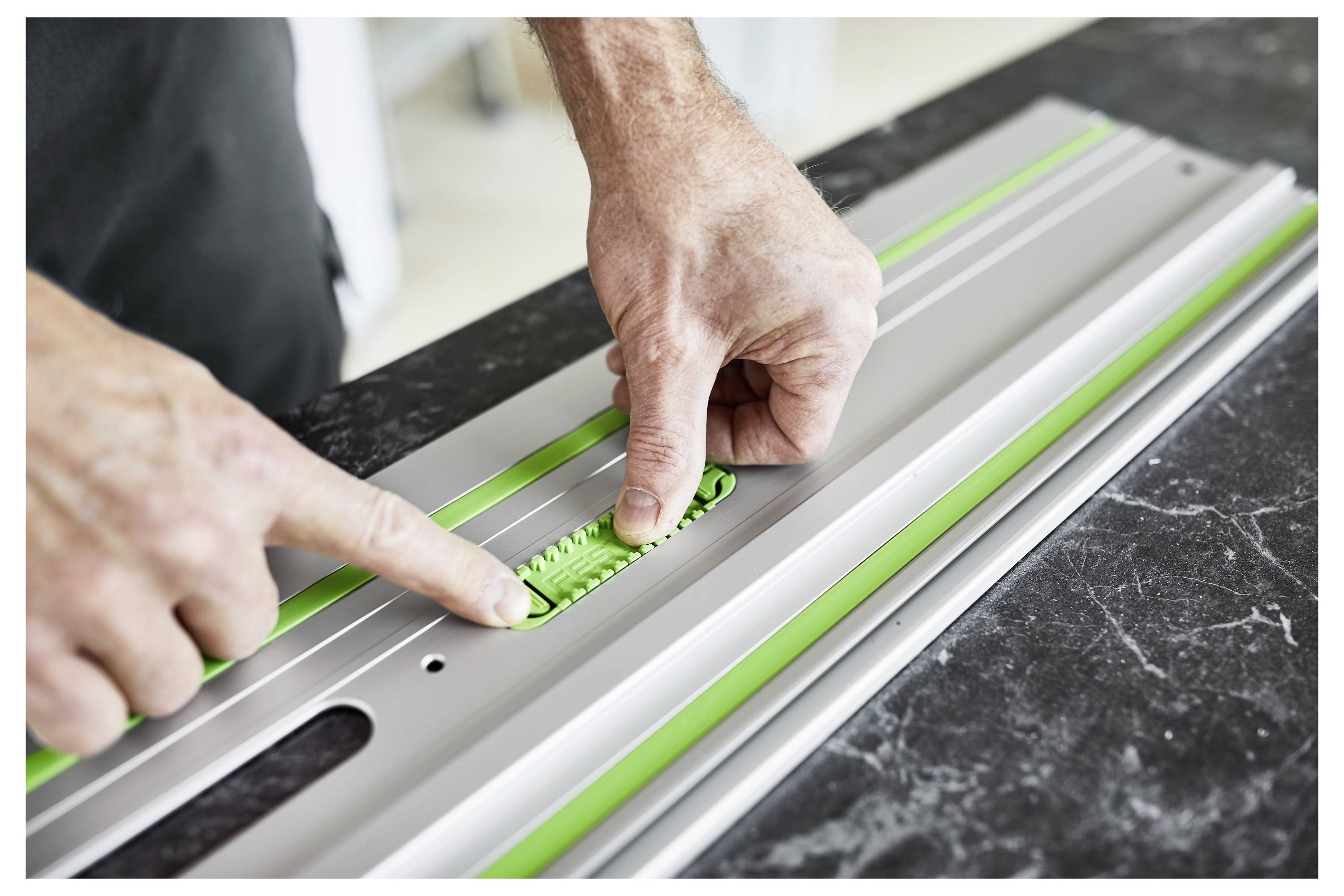 Eine Person verwendet eine Festool Tauchsäge, um ein Stück Holz auf einer Werkbank zu schneiden, wobei die Präzision und Sicherheitsmerkmale des Werkzeugs hervorgehoben werden.