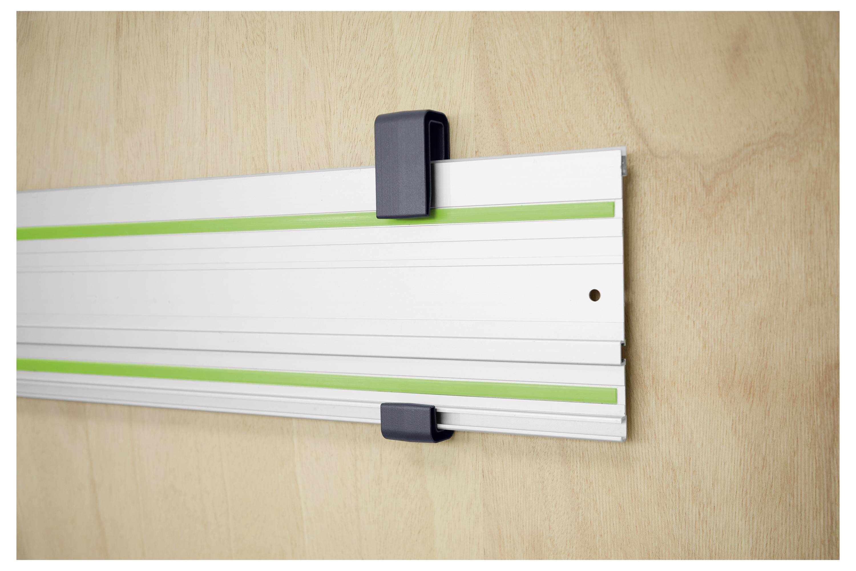 Eine Person verwendet einen tragbaren elektrischen Schleiffer auf einer Holzoberfläche zum Glätten. Der Schleiffer ist schwarz und grün und wird fest in einer Hand gehalten.