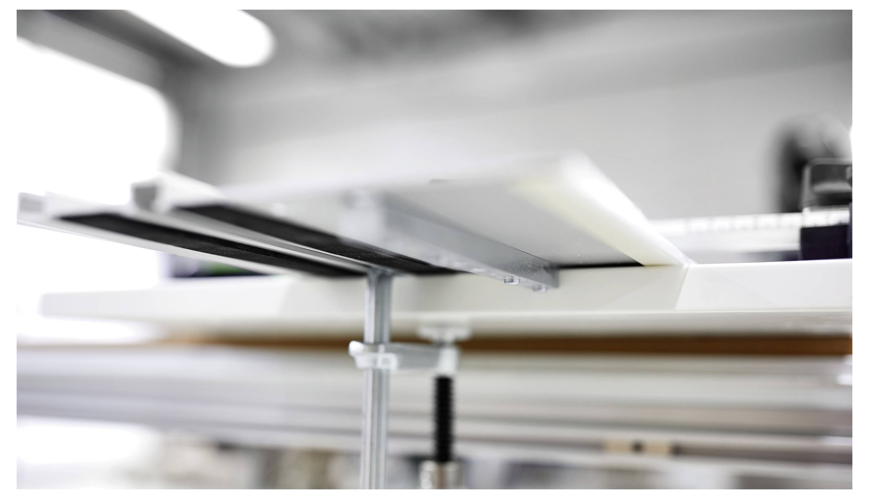 Eine Nahaufnahme eines mechanischen Aufbaus, der parallele Stangen und Bolzen zeigt, möglicherweise Teil eines 3D-Druckers oder einer CNC-Maschine, in einer Werkstattumgebung.