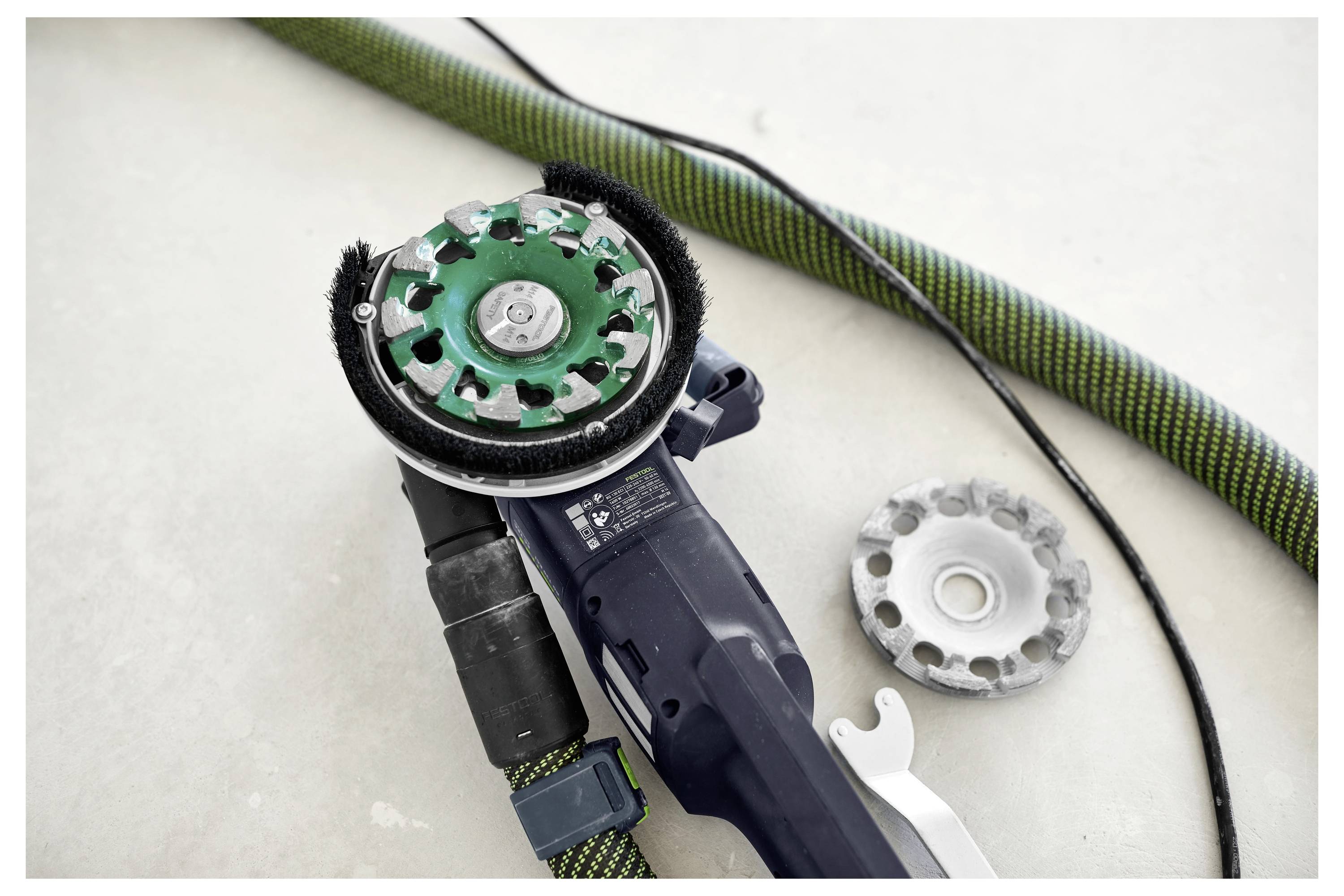 Ein Bauarbeiter in Schutzausrüstung bedient einen Elektroschrauber an einem Holzrahmen auf einer Baustelle, mit Gerüsten im Hintergrund.