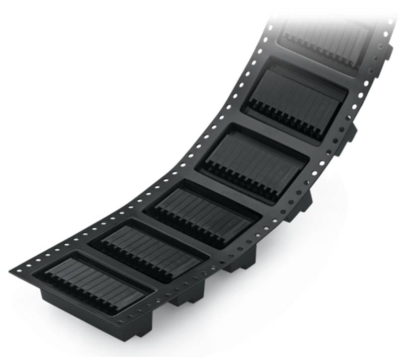 Ein gebogenes Band aus schwarzen integrierten Schaltkreisen in Spulenformat, häufig für die automatisierte Bestückung elektronischer Komponenten verwendet.