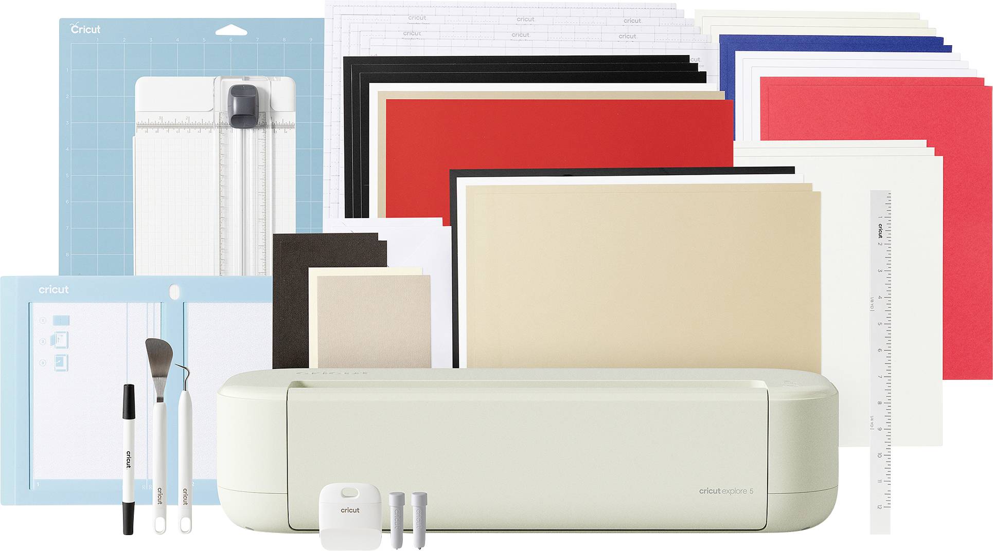 Eine Cricut-Maschine mit enthaltenen Werkzeugen, Schneidematten und verschiedenen Papier- und Vinylblättern in unterschiedlichen Farben für Bastelprojekte.