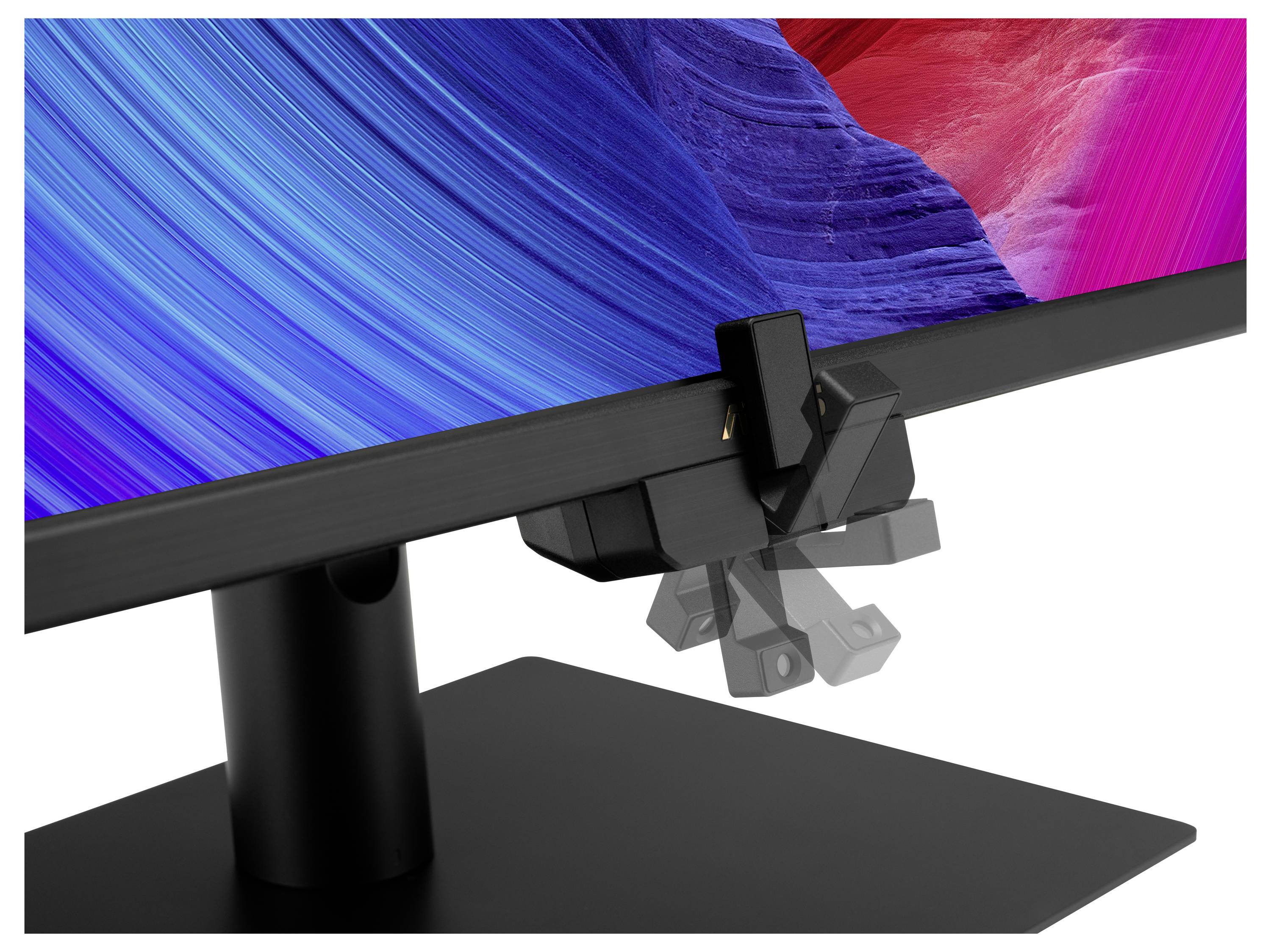 Nahaufnahme eines Computermonitors mit angebrachtem Farbkalibriersystem vor einem lebendigen abstrakten Hintergrund aus blauen und roten Wirbeln.