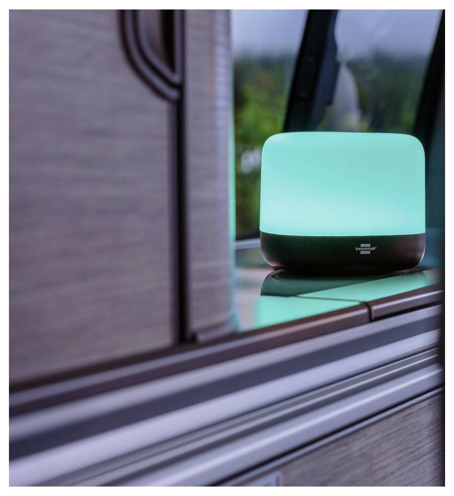 Eine türkisfarbene Diffuserlampe auf einem Holztresen in der Nähe eines Fensters, die ein weiches Licht ausstrahlt.