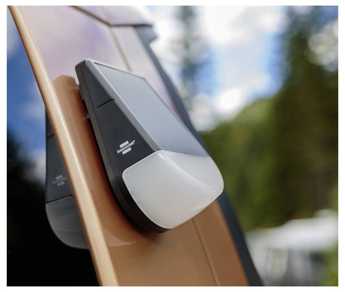 Ein solarbetriebenes Autolicht, das an der Außenseite eines Fahrzeugs angebracht ist und vor einem Hintergrund von Bäumen und Himmel montiert ist, was auf die Nutzung umweltfreundlicher Technologie hinweist.