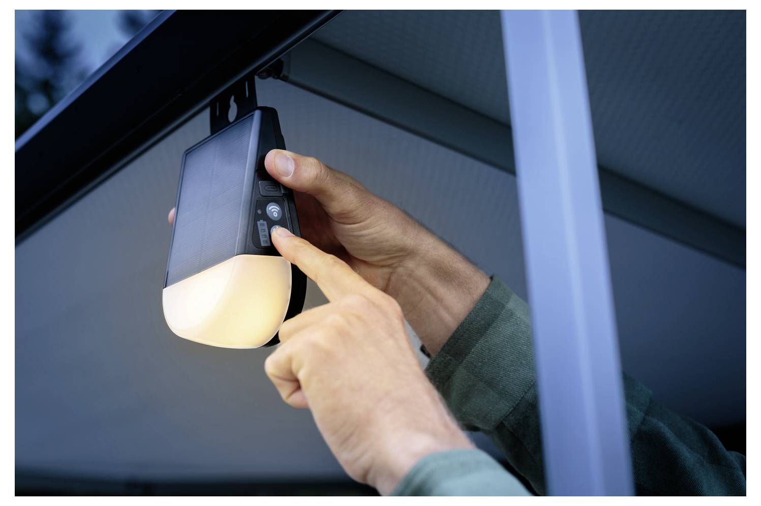 Eine Person stellt die Einstellungen einer montierten Außenleuchte ein.