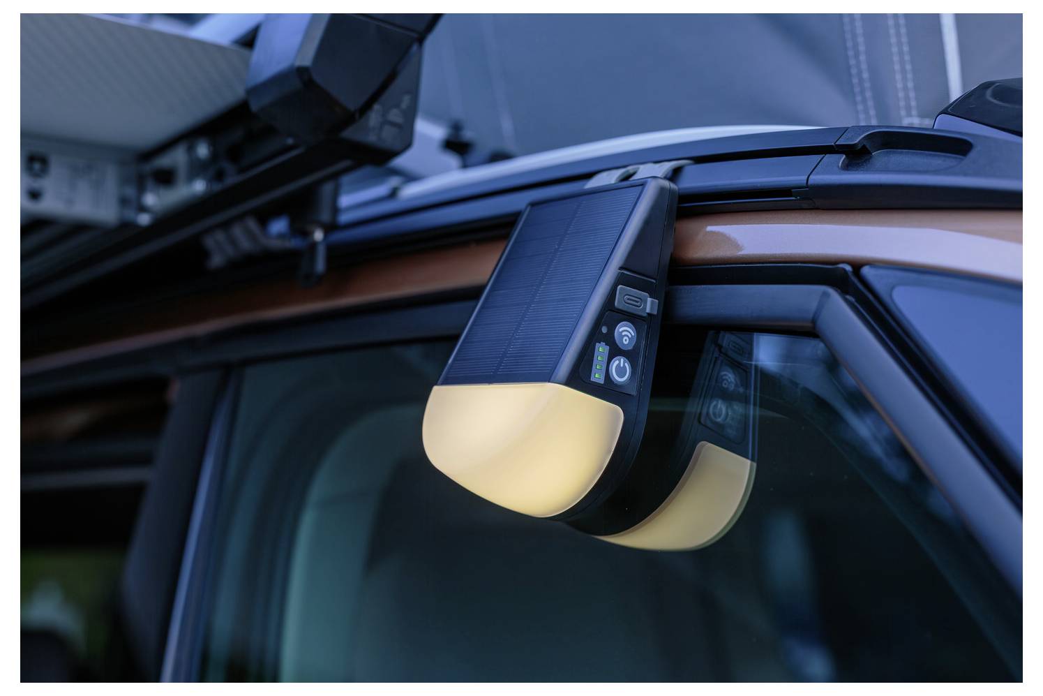 Ein auf einem Dachgepäckträger eines Fahrzeugs angebrachtes Gerät mit Tasten und einem Licht, wahrscheinlich zur Beleuchtung oder Signalisierung verwendet.