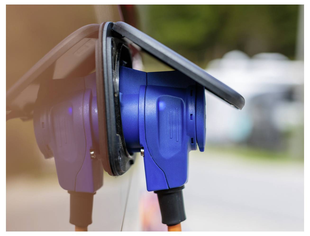 Blauer und schwarzer Stecker für Elektrofahrzeuge an einer Ladestation angeschlossen, in Nahaufnahme gezeigt.