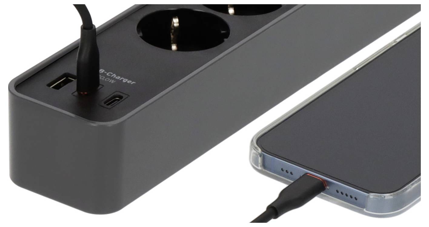 Eine Steckdosenleiste mit zwei USB-Anschlüssen und Steckdosen, die ein Smartphone über ein eingestecktes Kabel auflädt.