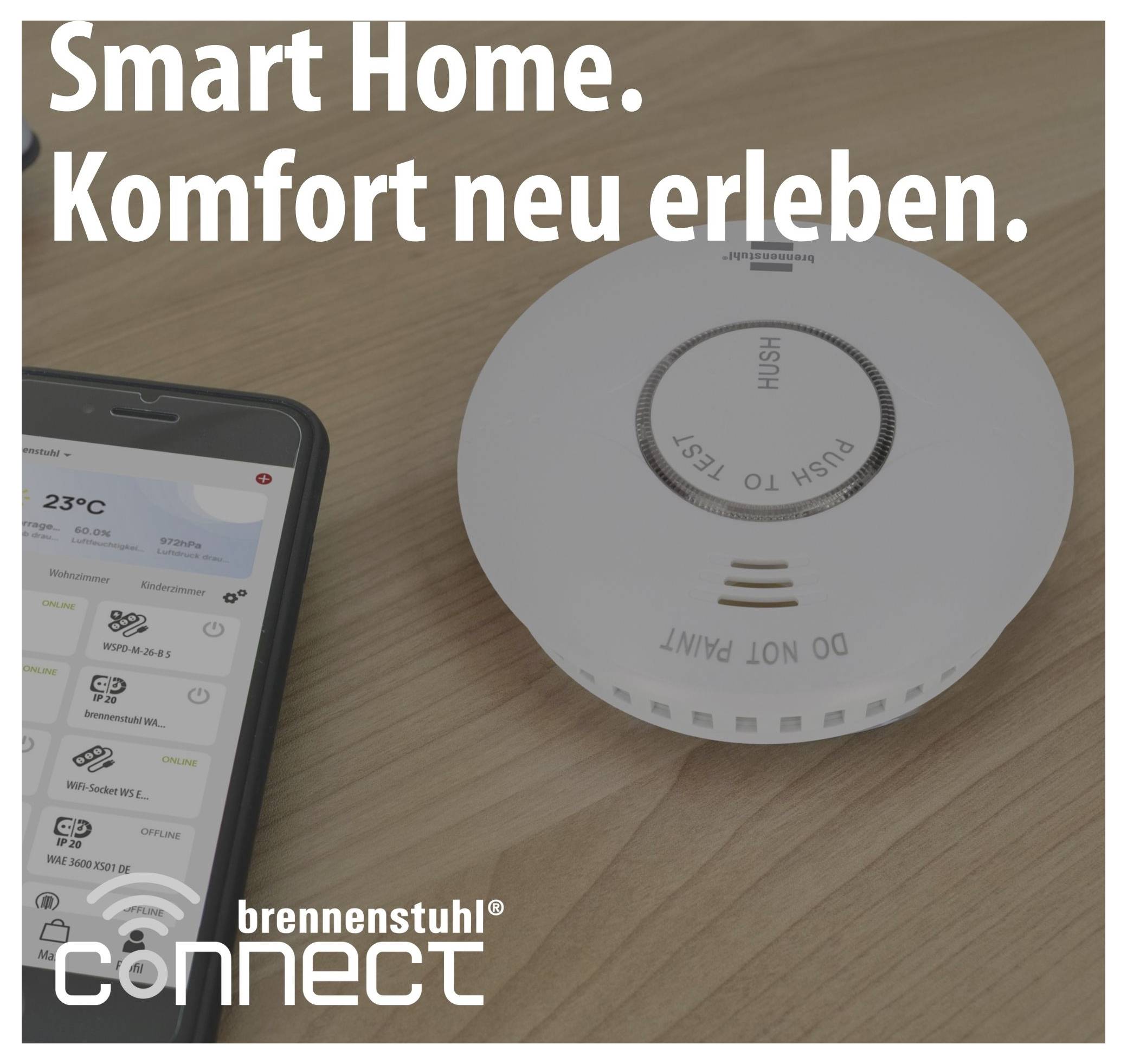 Werbeabbildung für Smart-Home: Smartphone-App steuert ein Brennenstuhl-connect-Gerät neben einem Rauchmelder auf Holztisch, mit Text 'Smart Home. Komfort neu erleben.'