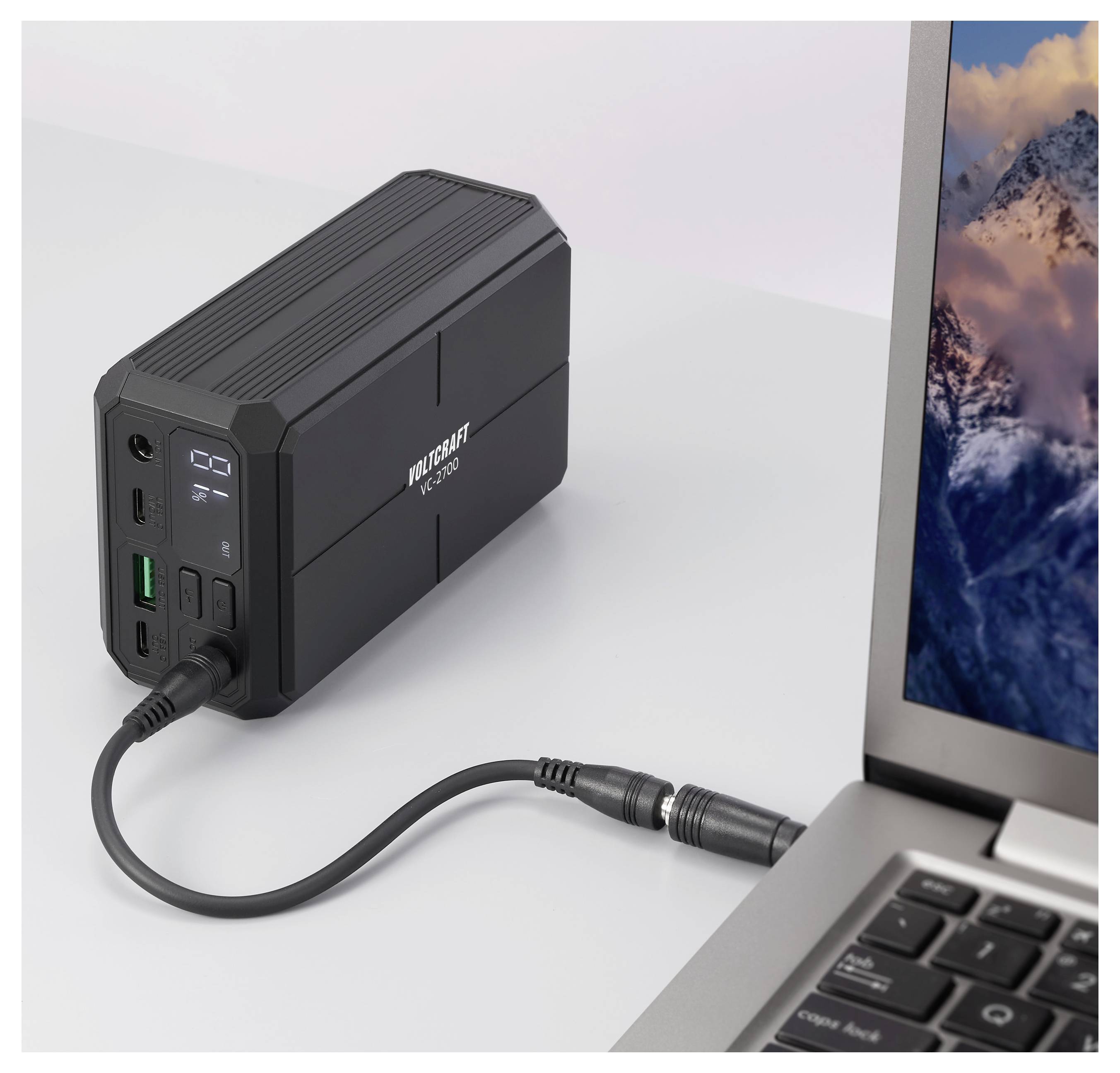 Tragbare Powerbank mit einem Laptop verbunden, mit Kabel und vorderer Anzeige, die den Batteriezustand und Ladeanschlüsse zeigt.