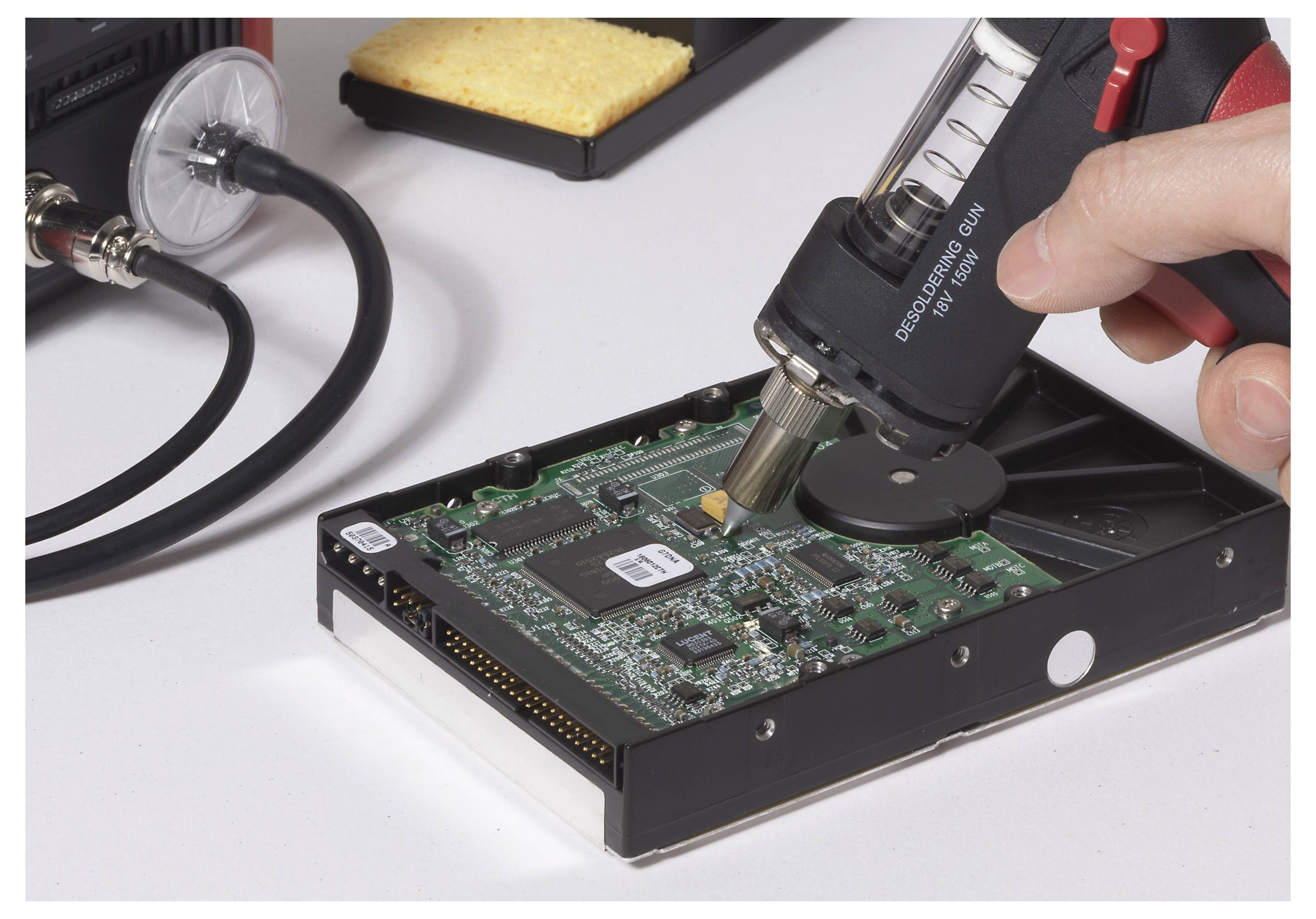 Eine Person verwendet eine Heißluftpistole, um an einer Computerfestplattenschaltung zu arbeiten, was auf einen Reparatur- oder Modifikationsprozess hindeutet.