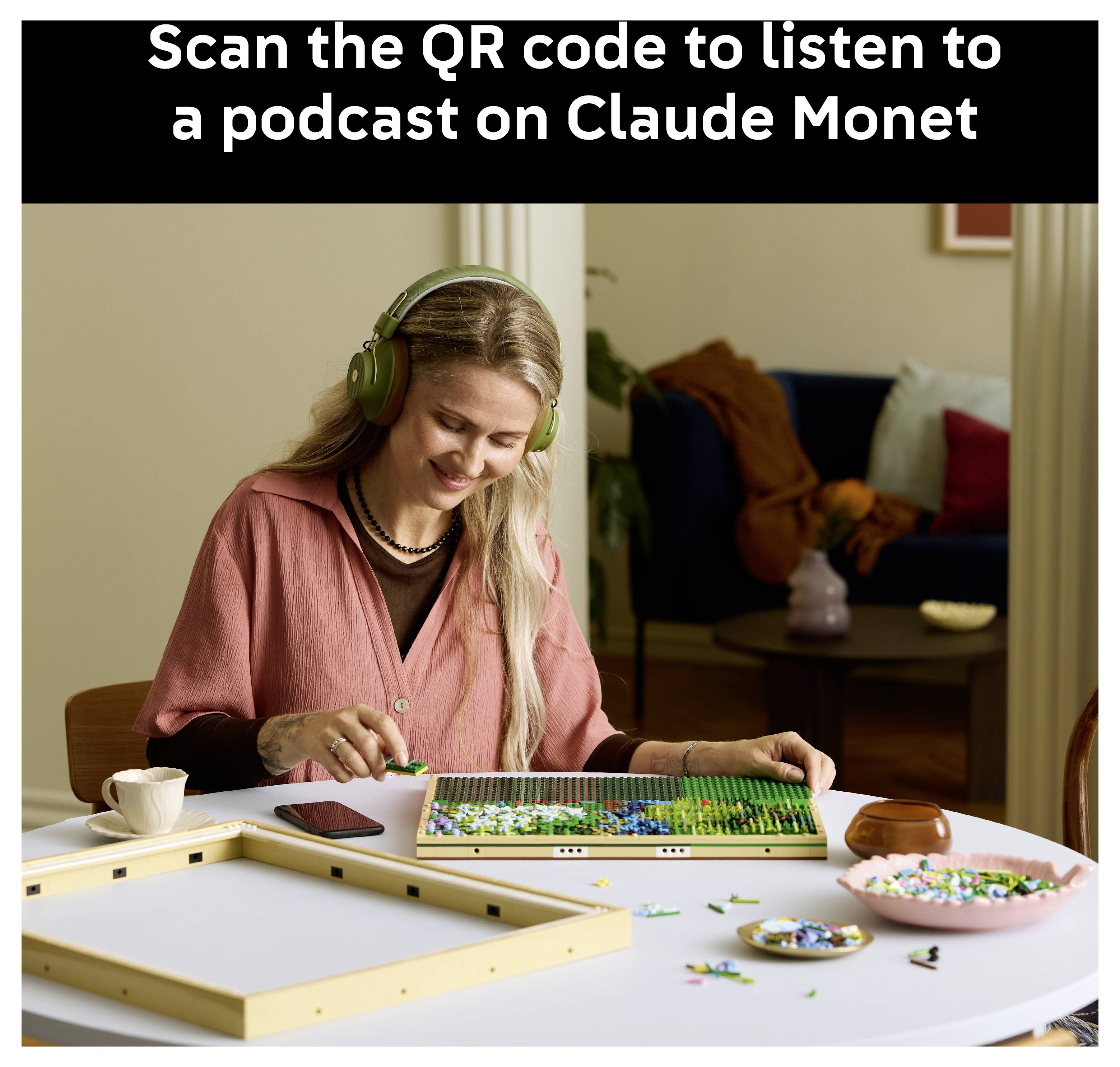 Eine Person mit Kopfhörern arbeitet an einem Puzzle auf einem Tisch. Der Text oben lautet „Scannen Sie den QR-Code, um einen Podcast über Claude Monet zu hören