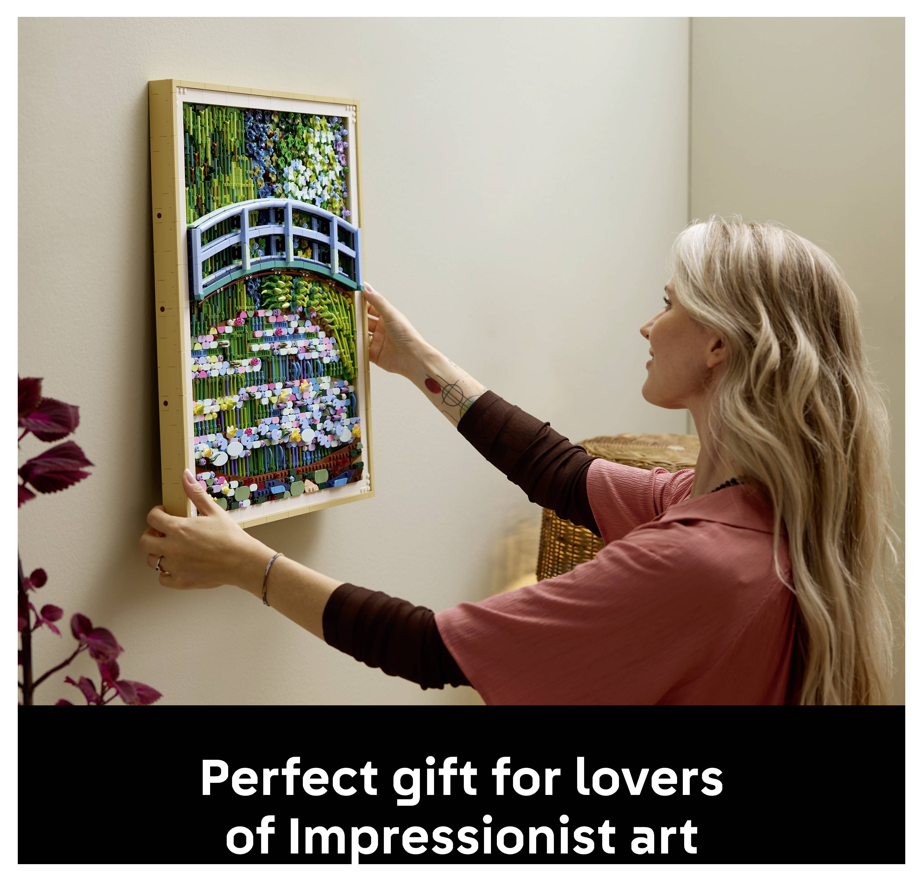 Eine Person hängt ein Kunstwerk in Rahmen einer Brücke über einen Seerosenteich an eine Wand. Der Text lautet: „Perfektes Geschenk für Liebhaber impressionistischer Kunst